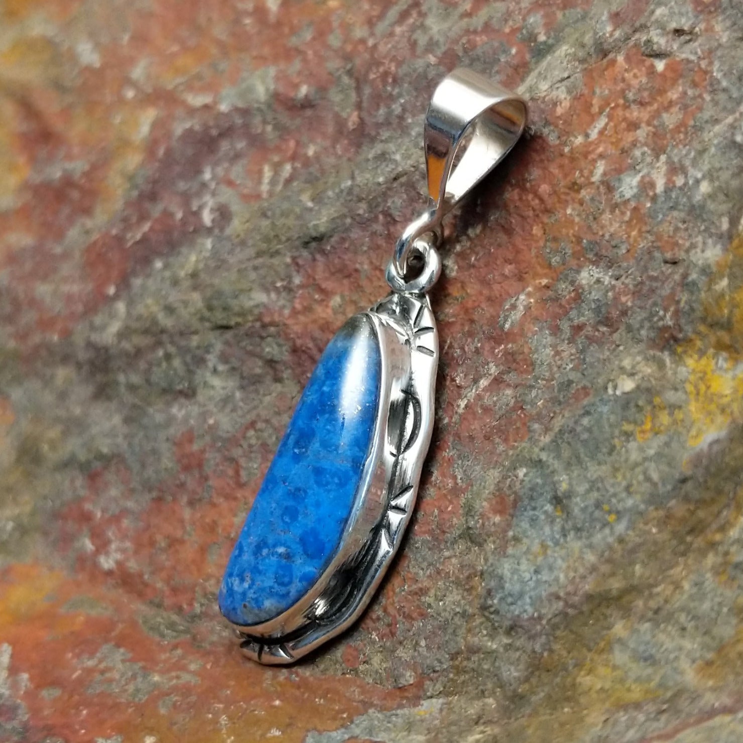 Sterling silver pendant with lapis set in the bezels and incised framing.