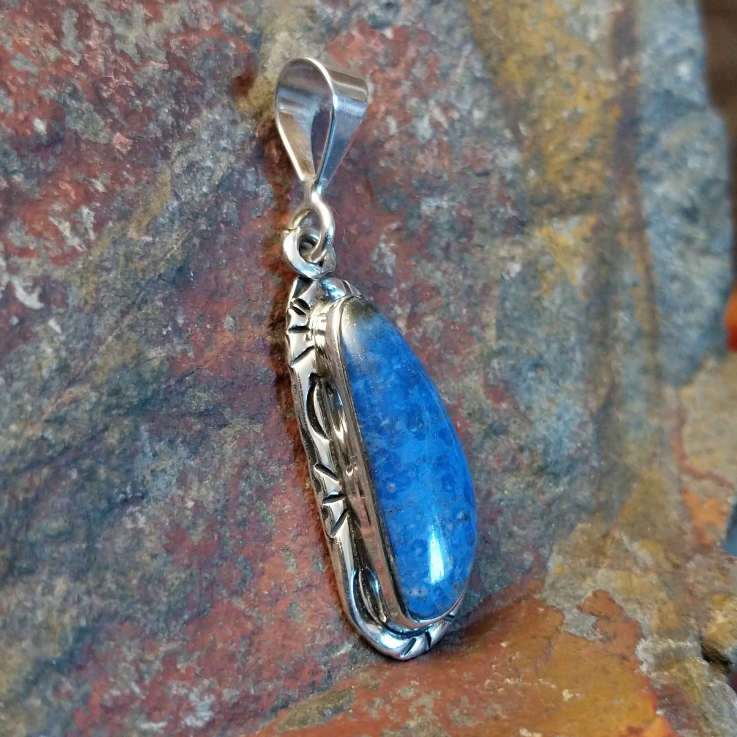 Sterling silver pendant with lapis set in the bezels and incised framing.
