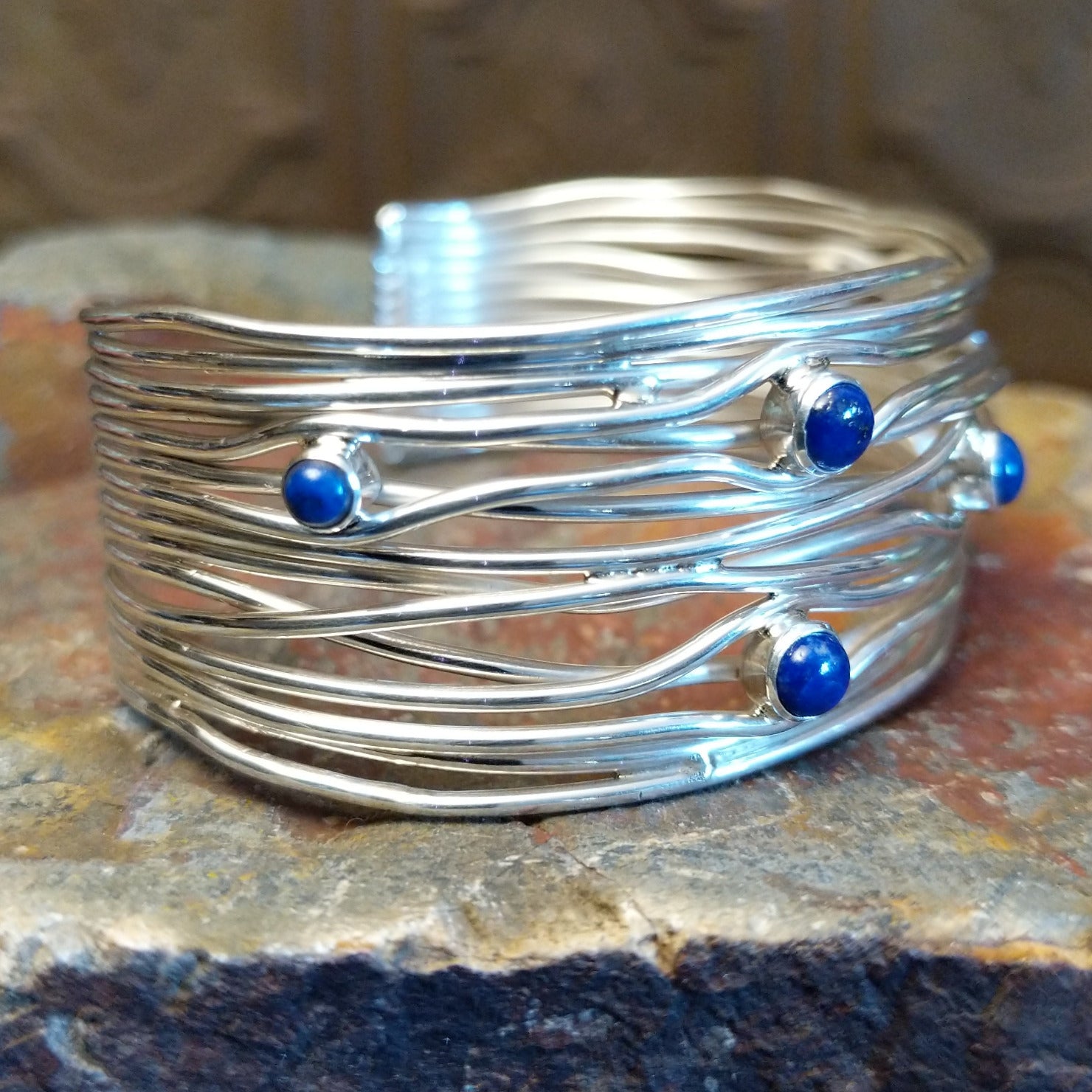Sterling silver cuff bracelet with layered strands and lapis set in bezels across the surface.