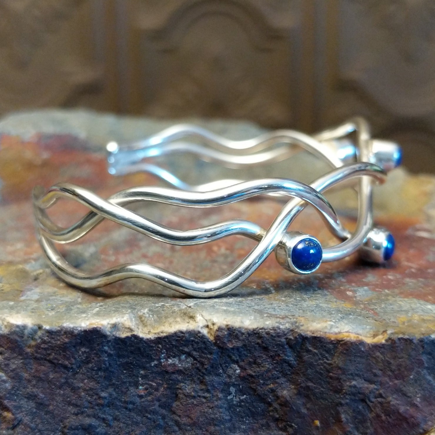 Sterling silver cuff bracelet with interwoven strand band and lapis set in scattered bezels.