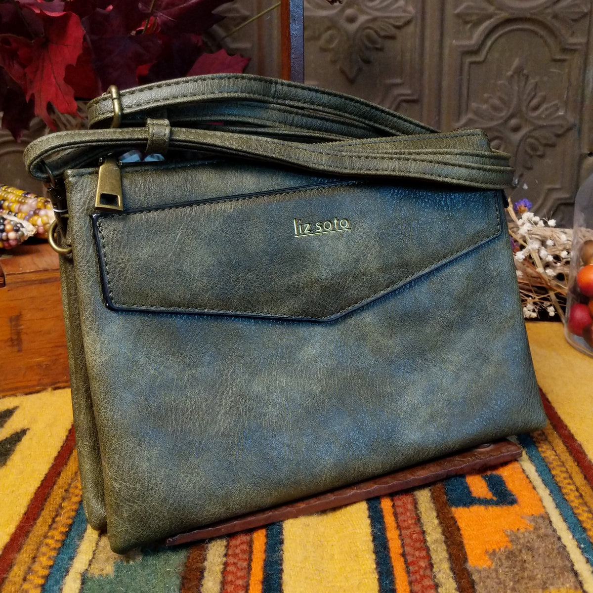 Lexi Crossbody Bag by Liz Soto featuring a streamlined silhouette, textured exterior, envelope-style front pocket, adjustable shoulder strap, metal hardware, and Liz Soto logo.