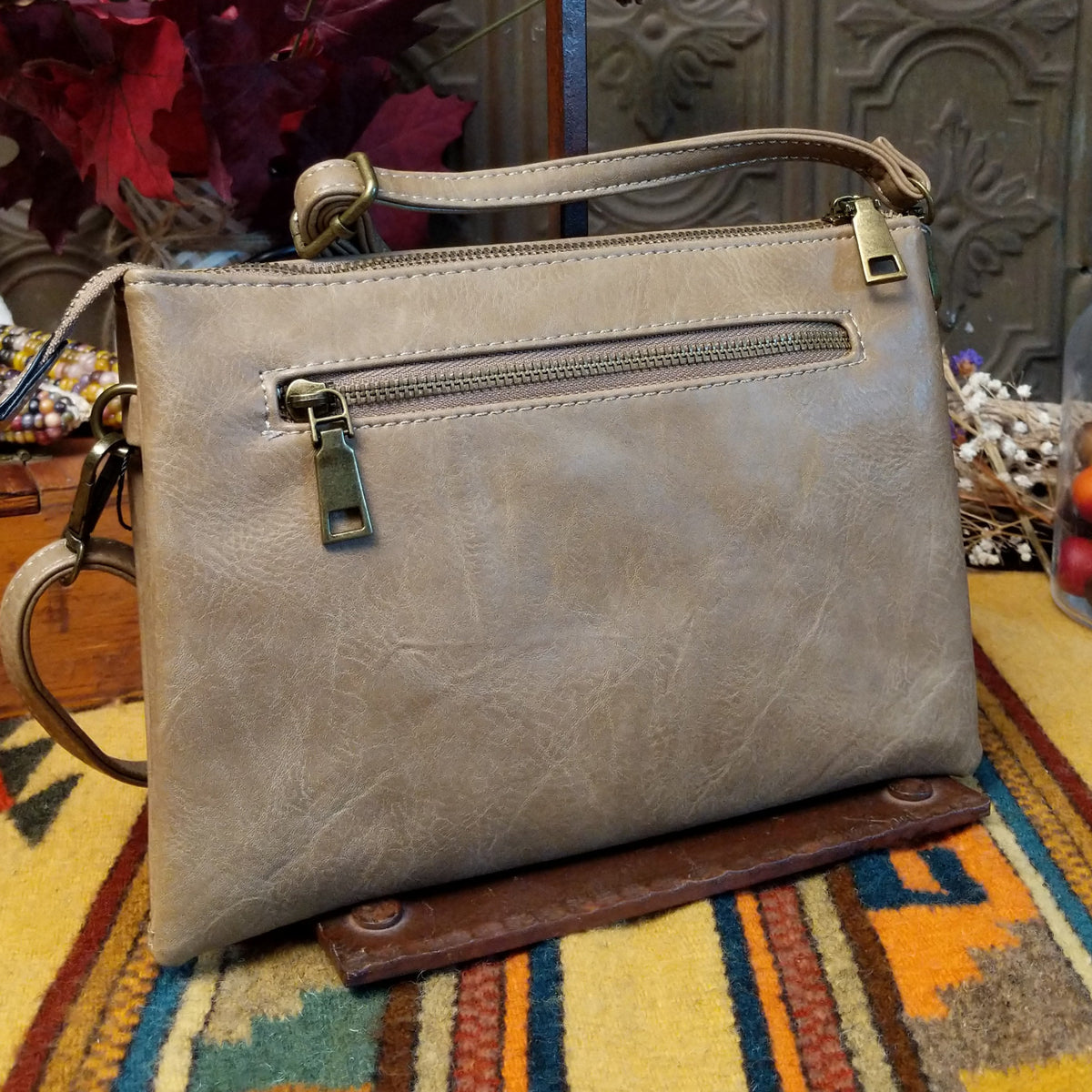 Lexi Crossbody Bag by Liz Soto featuring a streamlined silhouette, textured exterior, envelope-style front pocket, adjustable shoulder strap, metal hardware, and Liz Soto logo; back view.