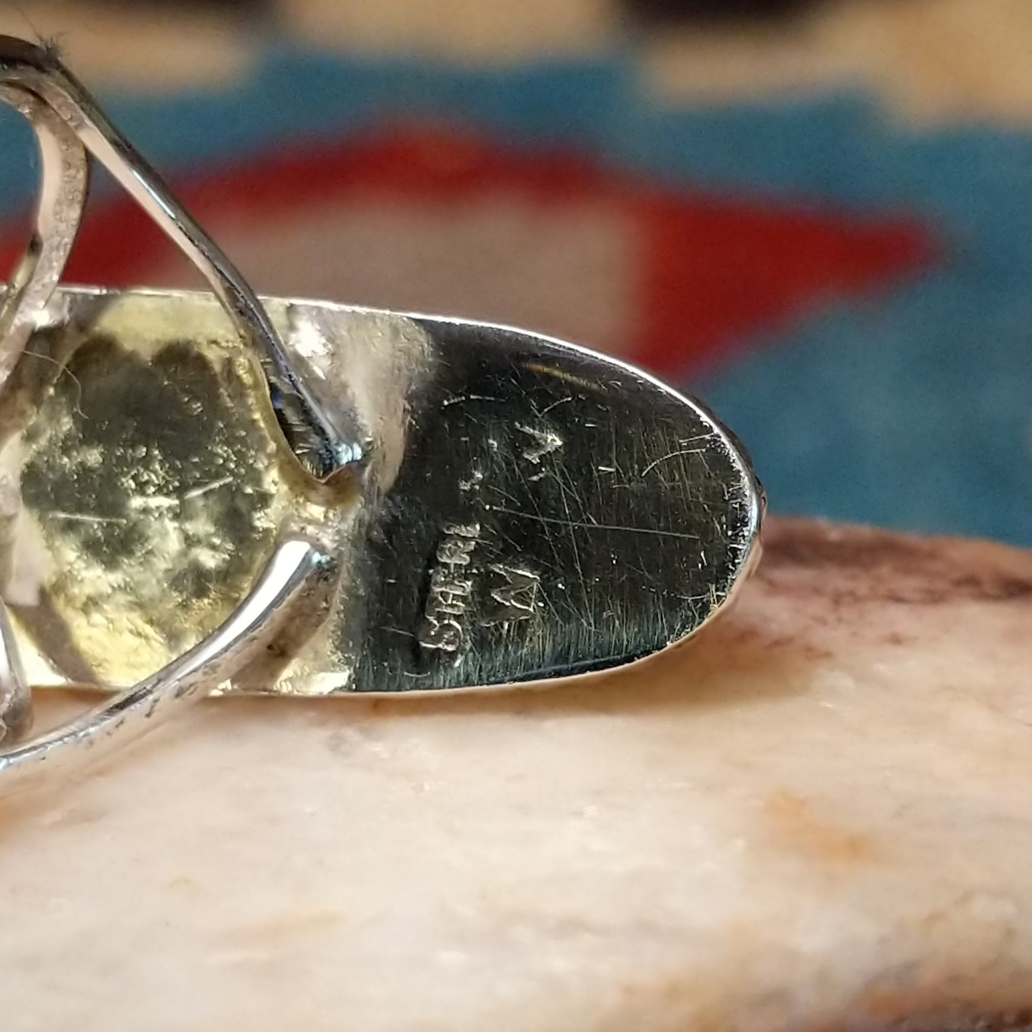 Long oval manmade opal ring by Wilbur Wauneka, featuring a shimmering oval opal with vibrant flashes of color set in a handcrafted sterling silver band. Artisan and Sterling Silver stamp.