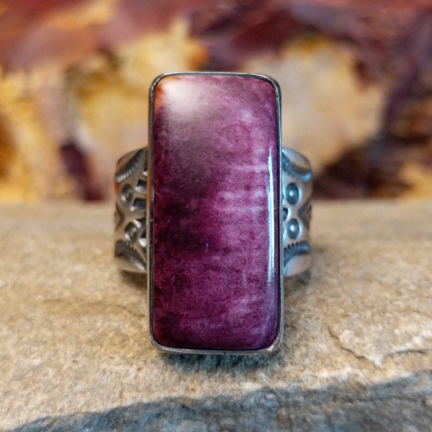 Long rectangular purple spiny oyster shell set in a smooth bezel with an intricately stamped band.