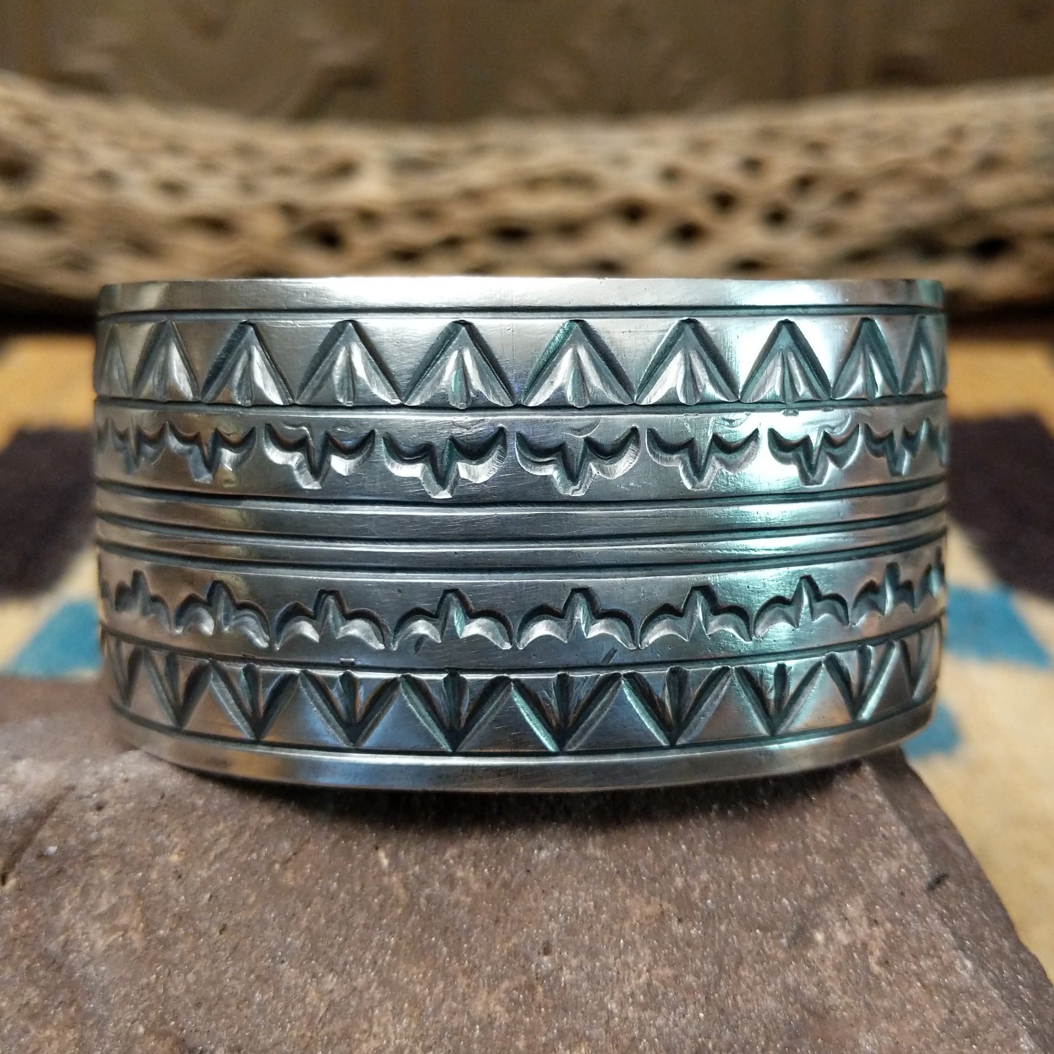Longhorn stamped sterling silver cuff by E. Piaso, featuring bold geometric hand-stamped longhorn-inspired patterns on a handcrafted wide sterling silver open cuff.