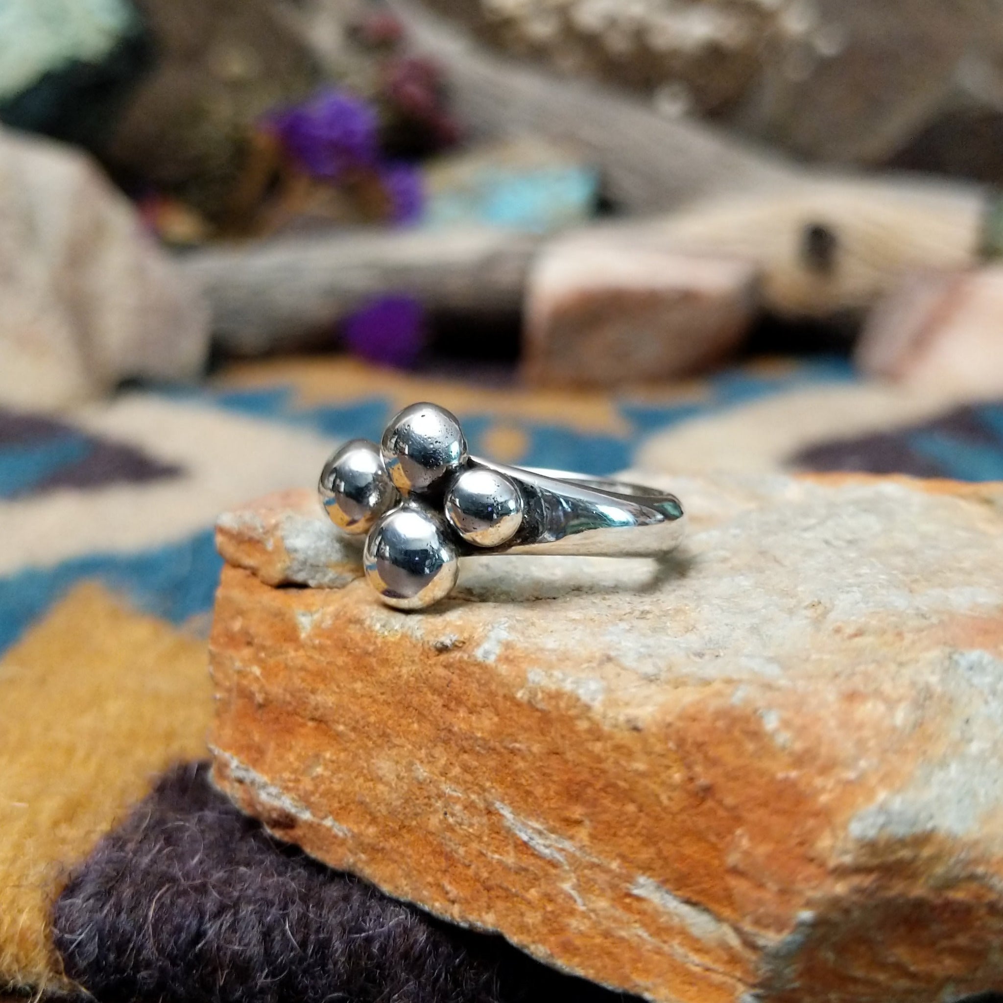 Handcrafted Navajo sterling silver ring by Leon Martinez featuring four graduated polished silver domes in a modern open-loop design with a high-polish finish; side view.