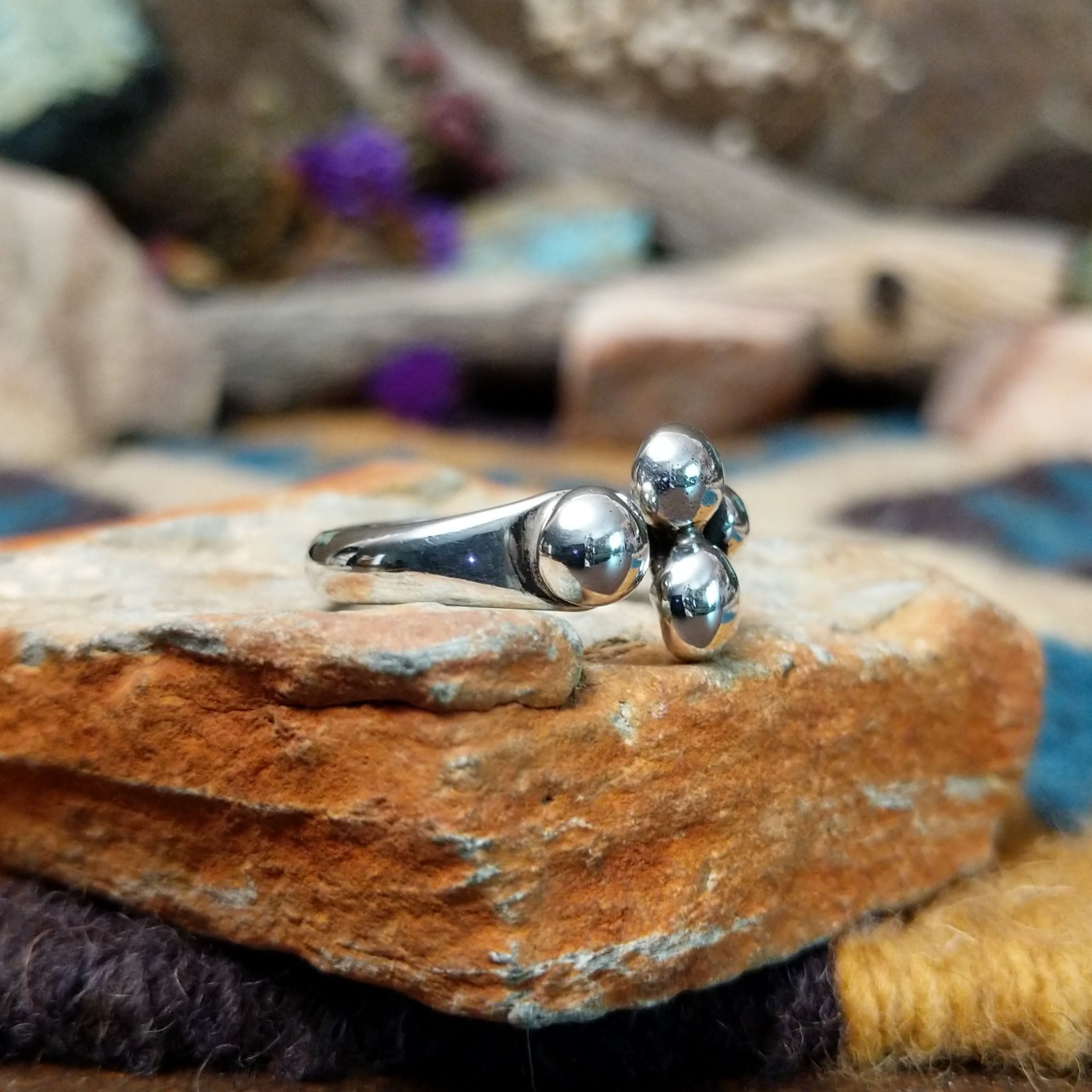 Handcrafted Navajo sterling silver ring by Leon Martinez featuring four graduated polished silver domes in a modern open-loop design with a high-polish finish; side view.