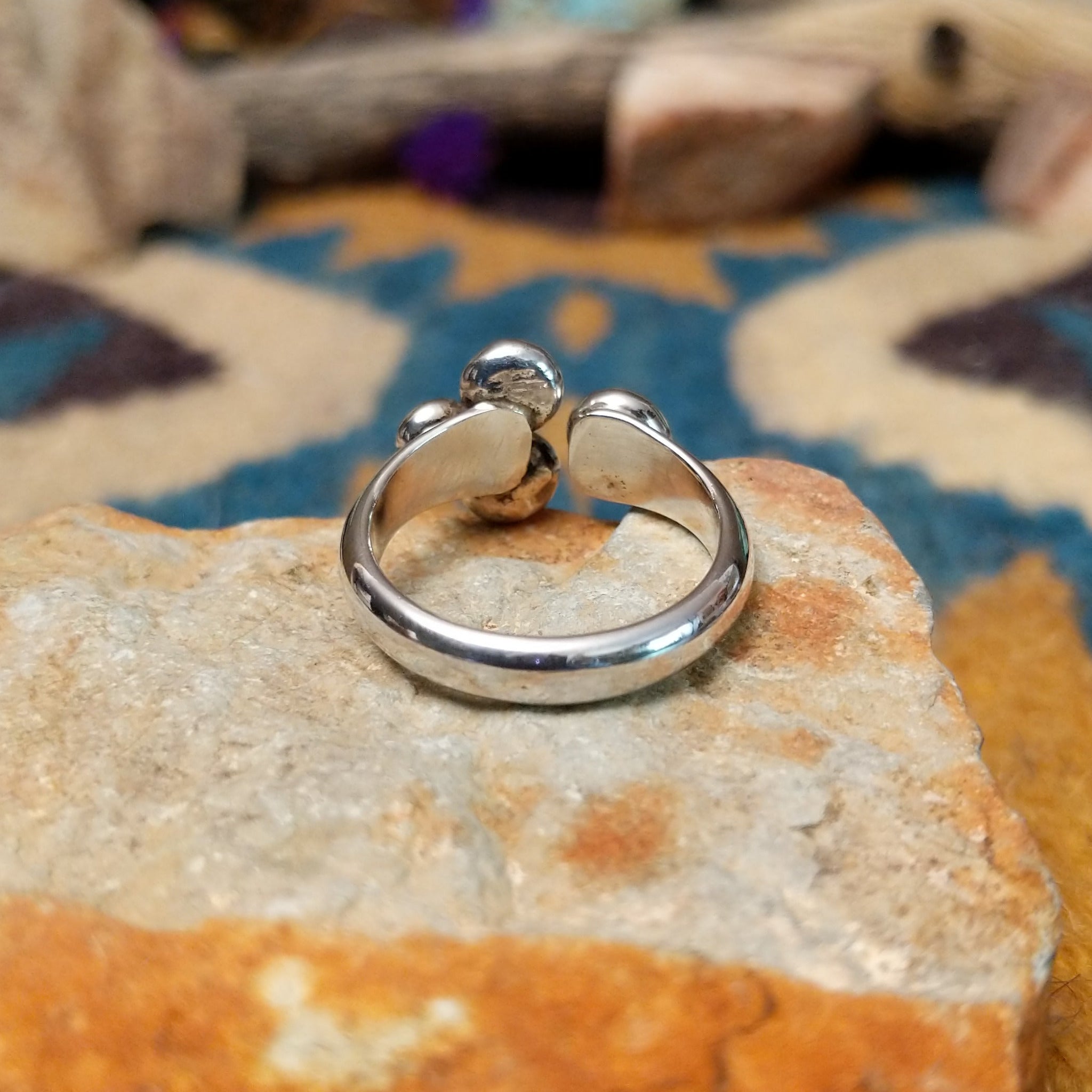 Handcrafted Navajo sterling silver ring by Leon Martinez featuring four graduated polished silver domes in a modern open-loop design with a high-polish finish; underside view.