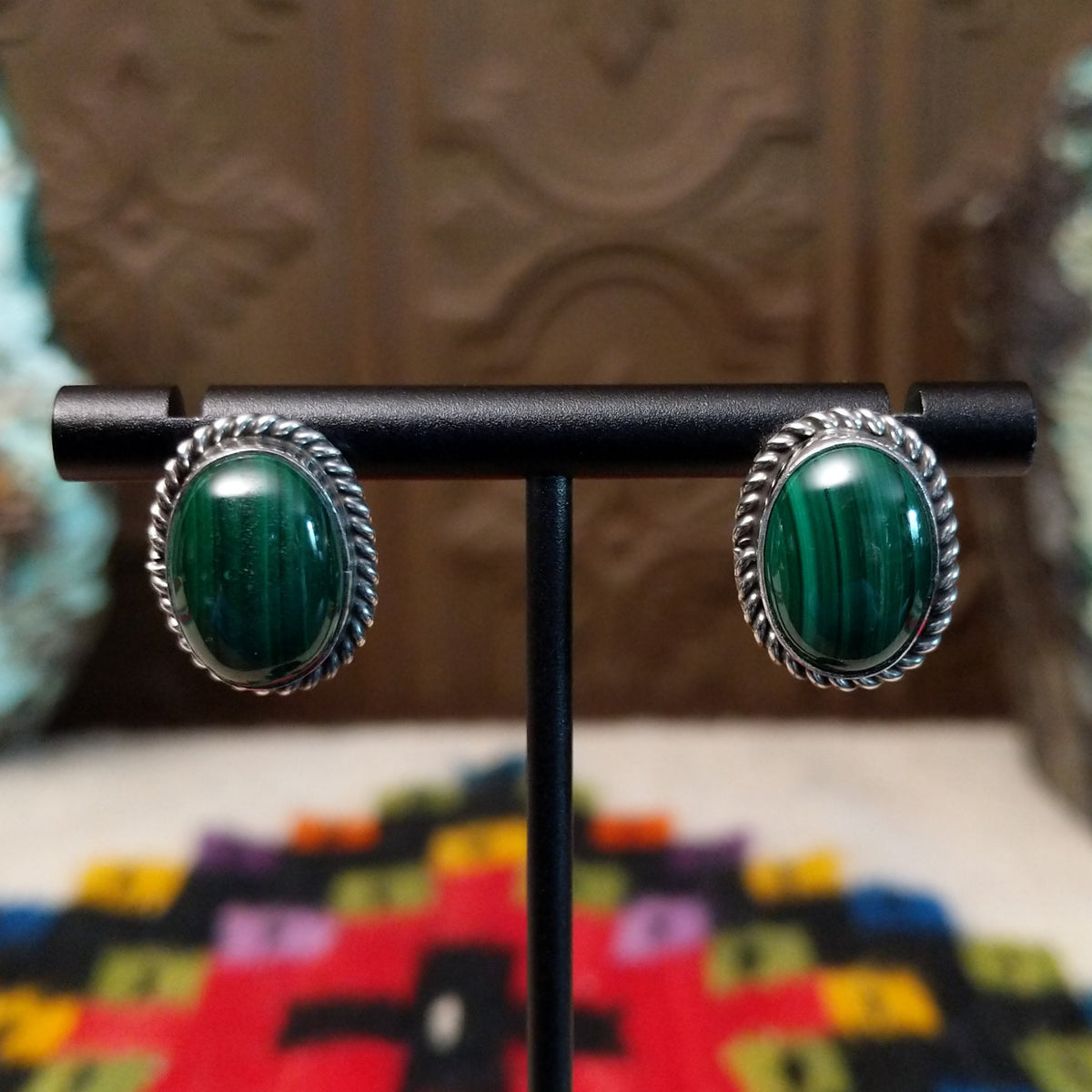 Malachite Oval Earrings by Priscilla Smith featuring polished deep-green malachite cabochons with natural banding, set in silver with twisted rope-style borders.