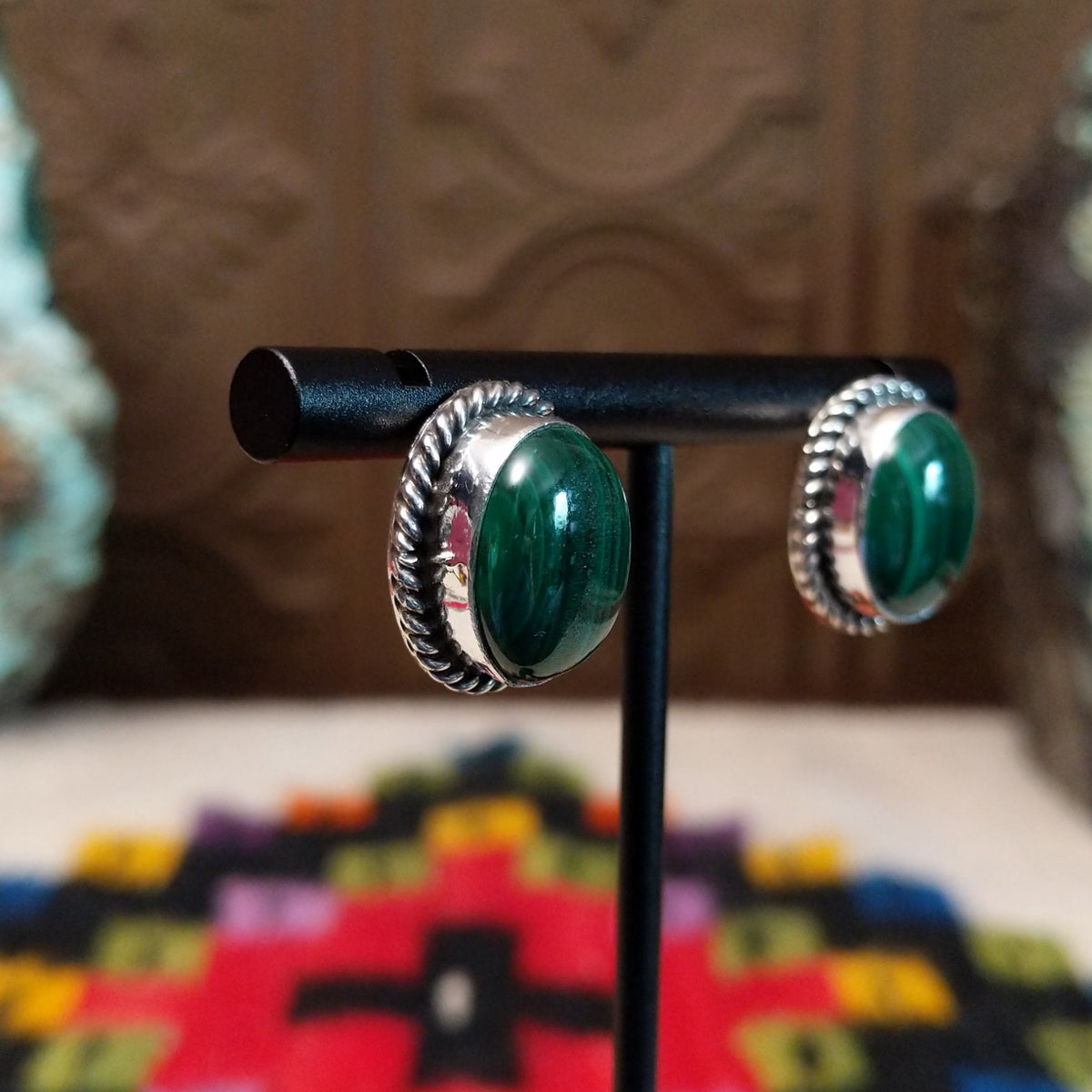 Malachite Oval Earrings by Priscilla Smith featuring polished deep-green malachite cabochons with natural banding, set in silver with twisted rope-style borders; side view.