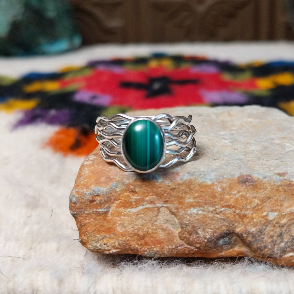 Malachite ring by Angela Martin with an oval banded stone and multi-strand wavy silver band.