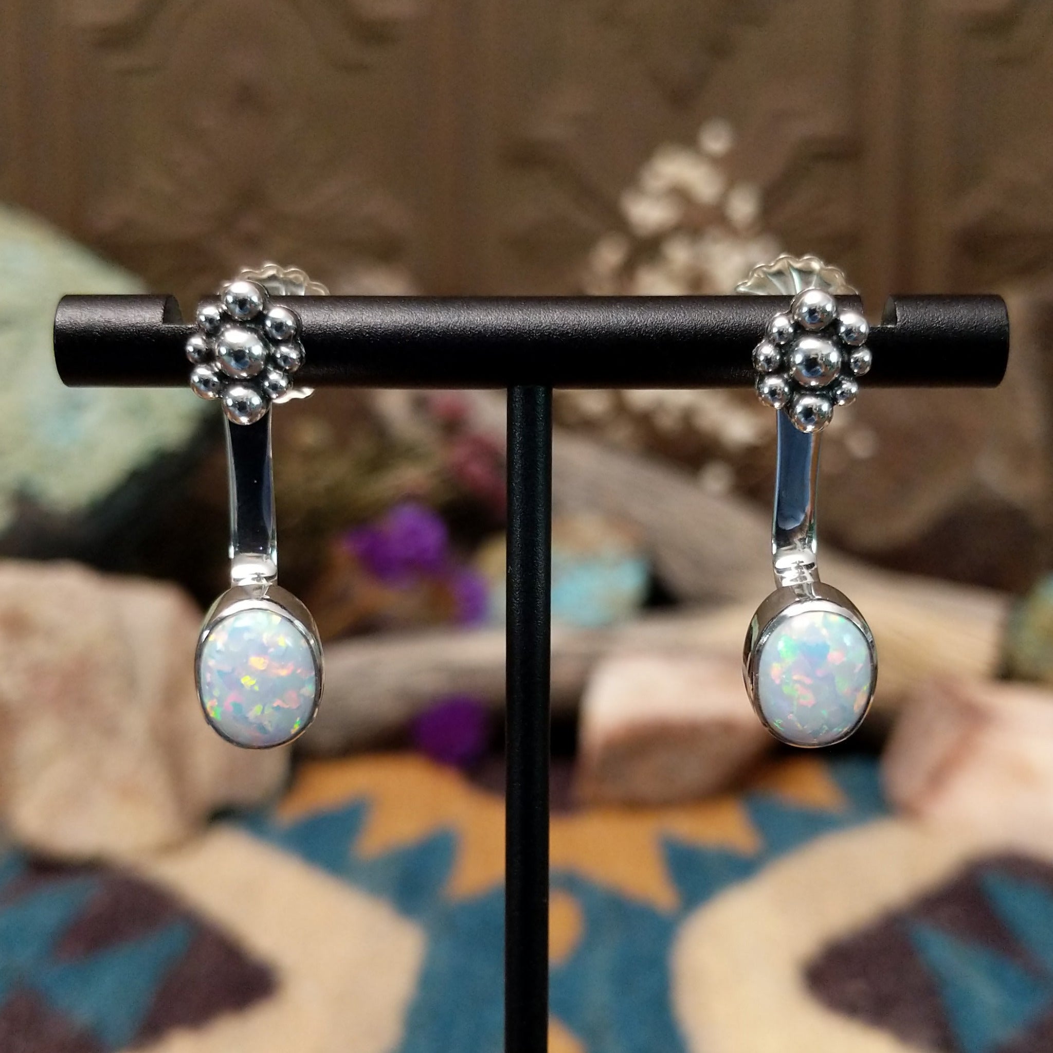 Handcrafted sterling silver adjustable earrings by Terry Wood featuring oval manmade opal cabochons with colorful iridescence and traditional Navajo silver bead cluster accents.