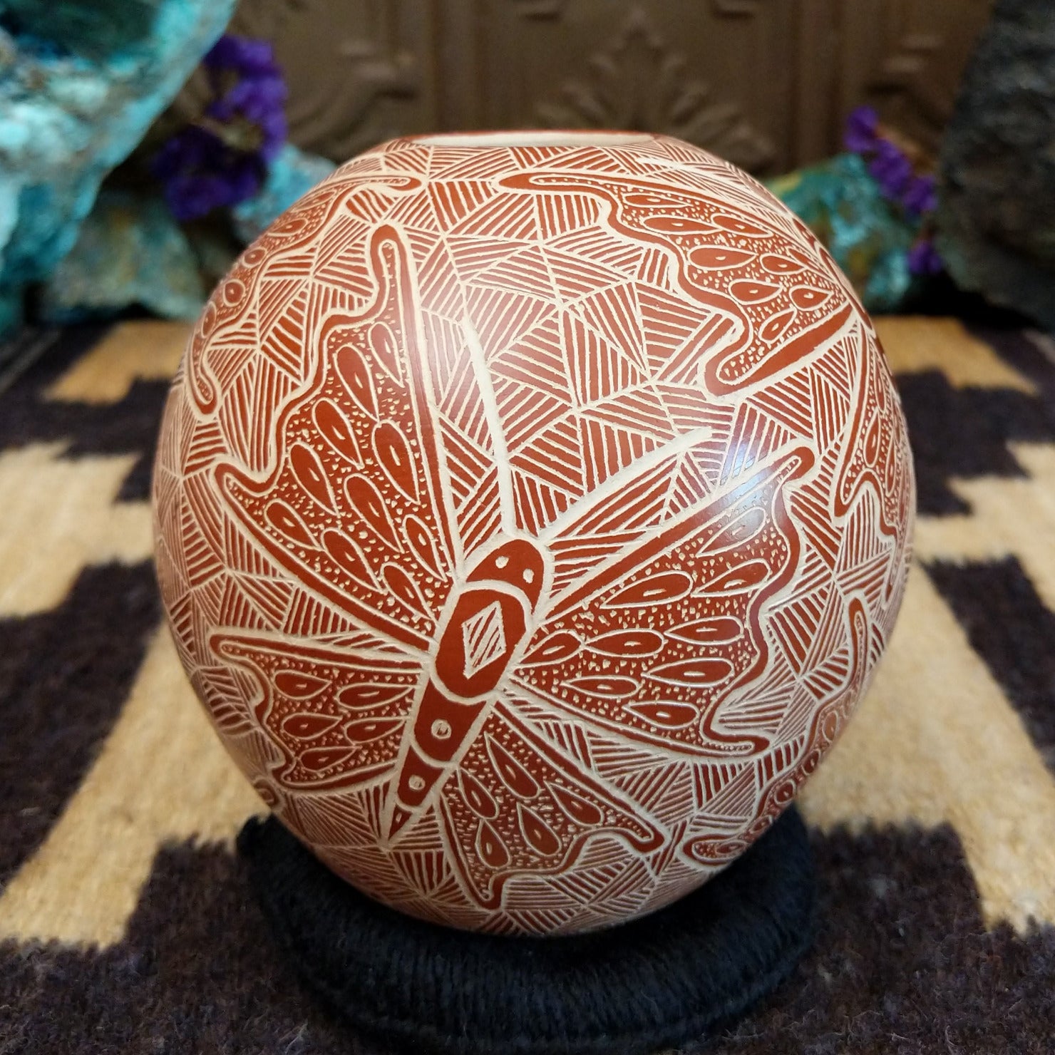Round Mata Ortiz pottery vessel featuring an etched butterfly design in warm clay tones with intricate geometric linework across the surface.