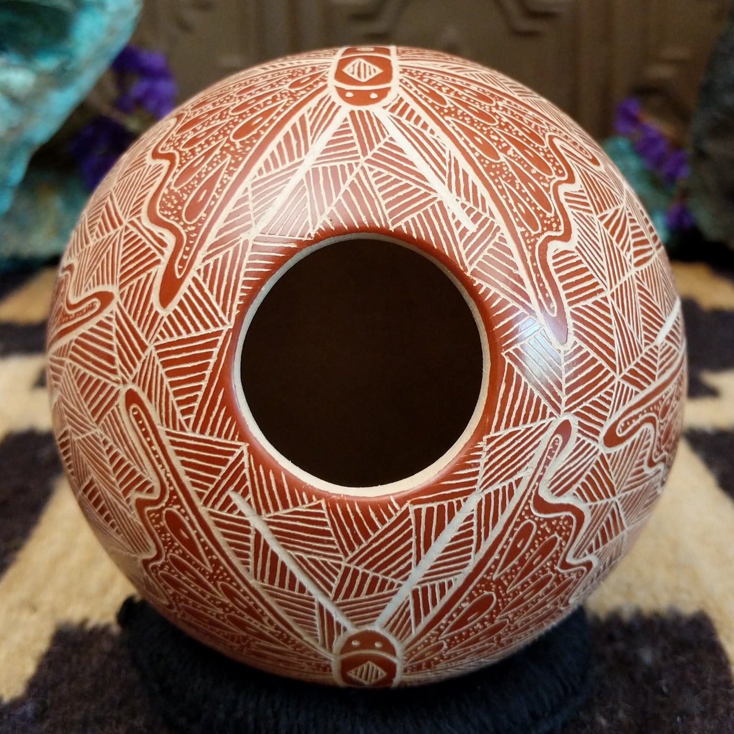 Round Mata Ortiz pottery vessel featuring an etched butterfly design in warm clay tones with intricate geometric linework across the surface.