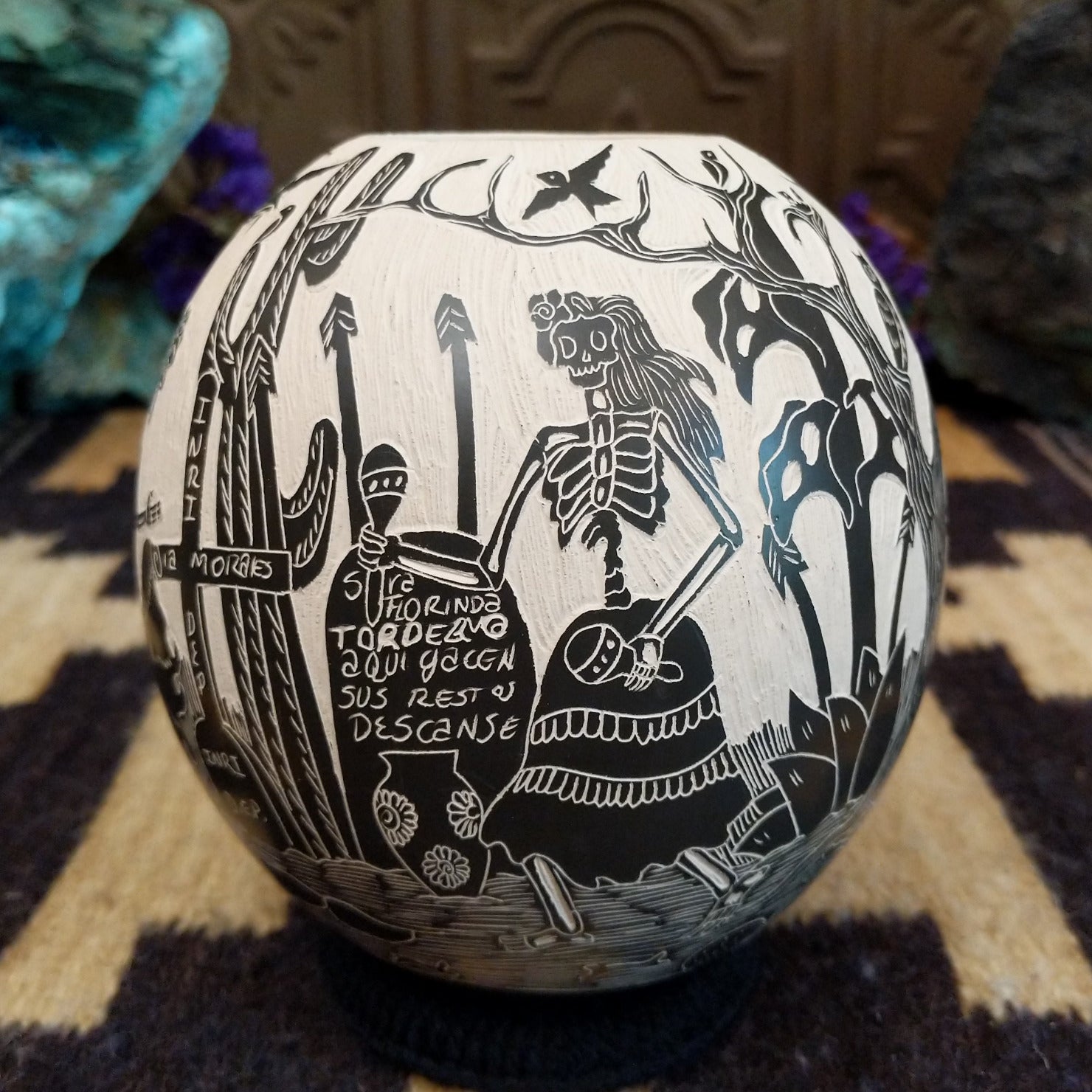 Round Mata Ortiz pottery vessel featuring an etched black and white Day of the Dead scene.