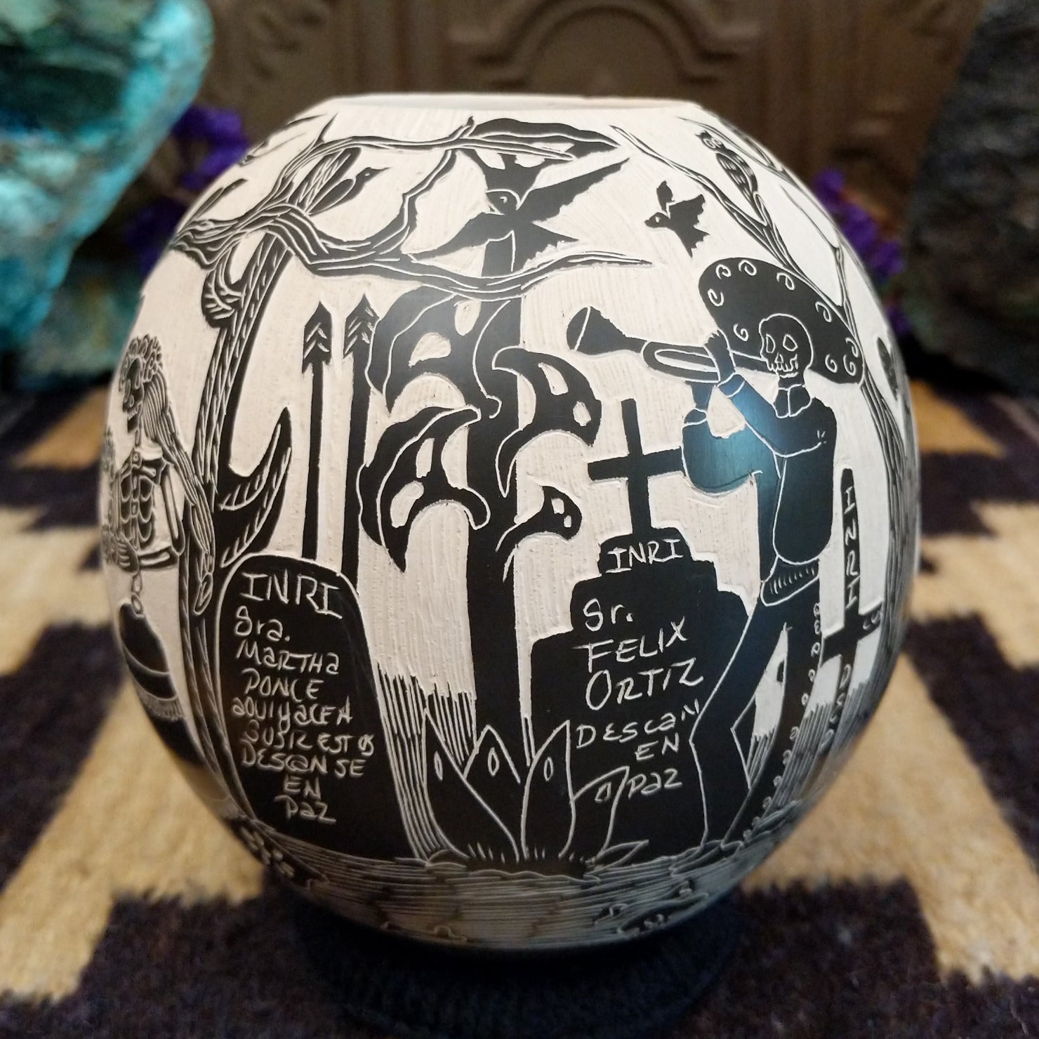 Round Mata Ortiz pottery vessel featuring an etched black and white Day of the Dead scene.