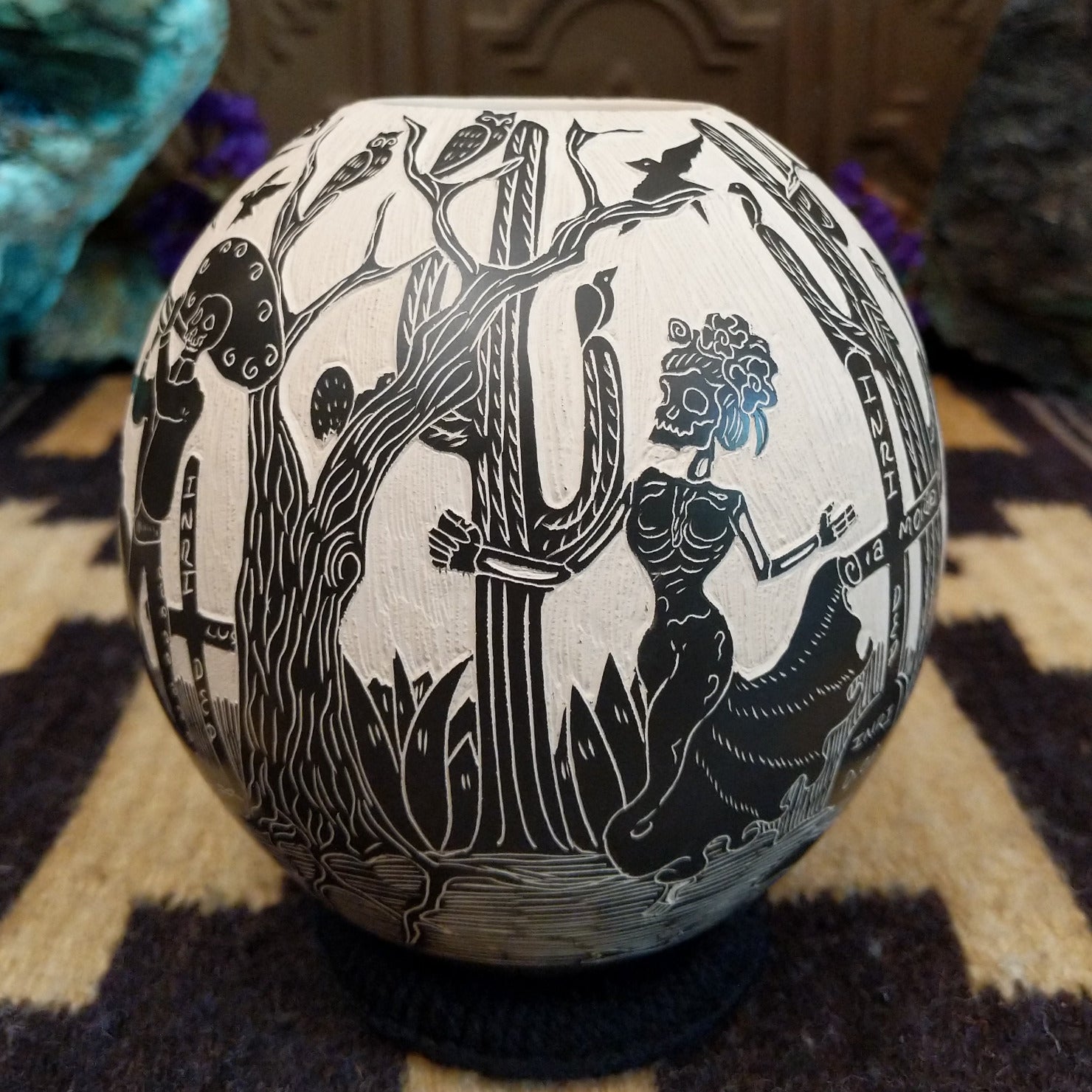 Round Mata Ortiz pottery vessel featuring an etched black and white Day of the Dead scene.