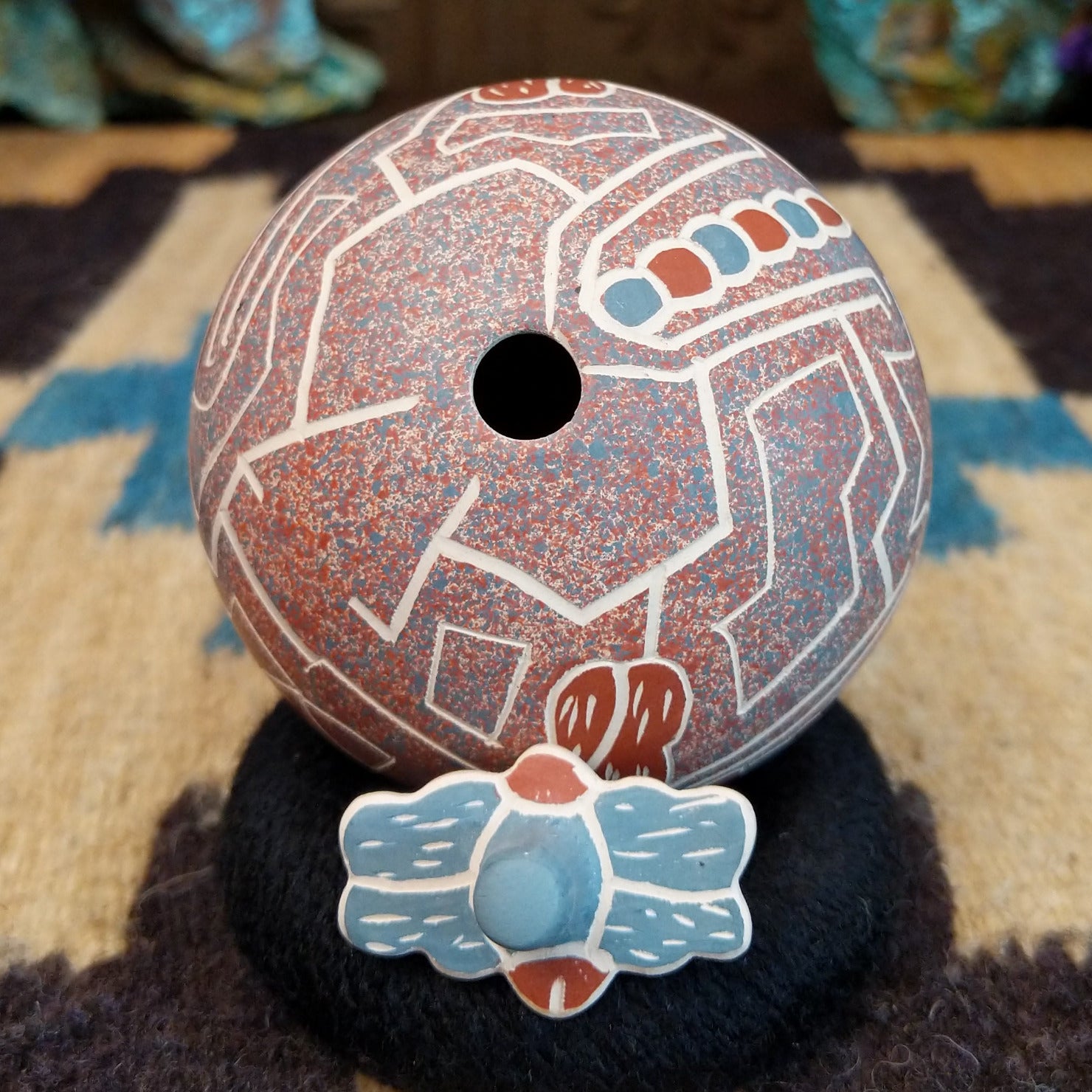 Round lidded Mata Ortiz pottery vessel featuring a dragonfly design in blue and clay tones with etched geometric background patterns.