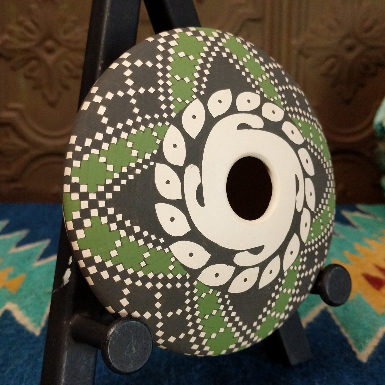 White clay seed pot with symmetrical designs painted in the colors green, black, and white.