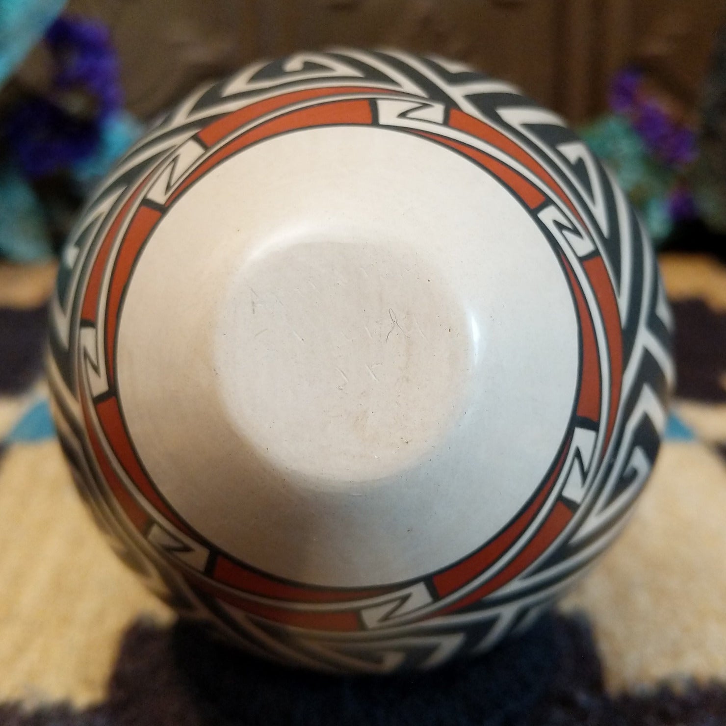 Mata Ortiz pottery vase with a cream rim, featuring bold black and cream triangle spiral patterns with warm clay accents near the neck.