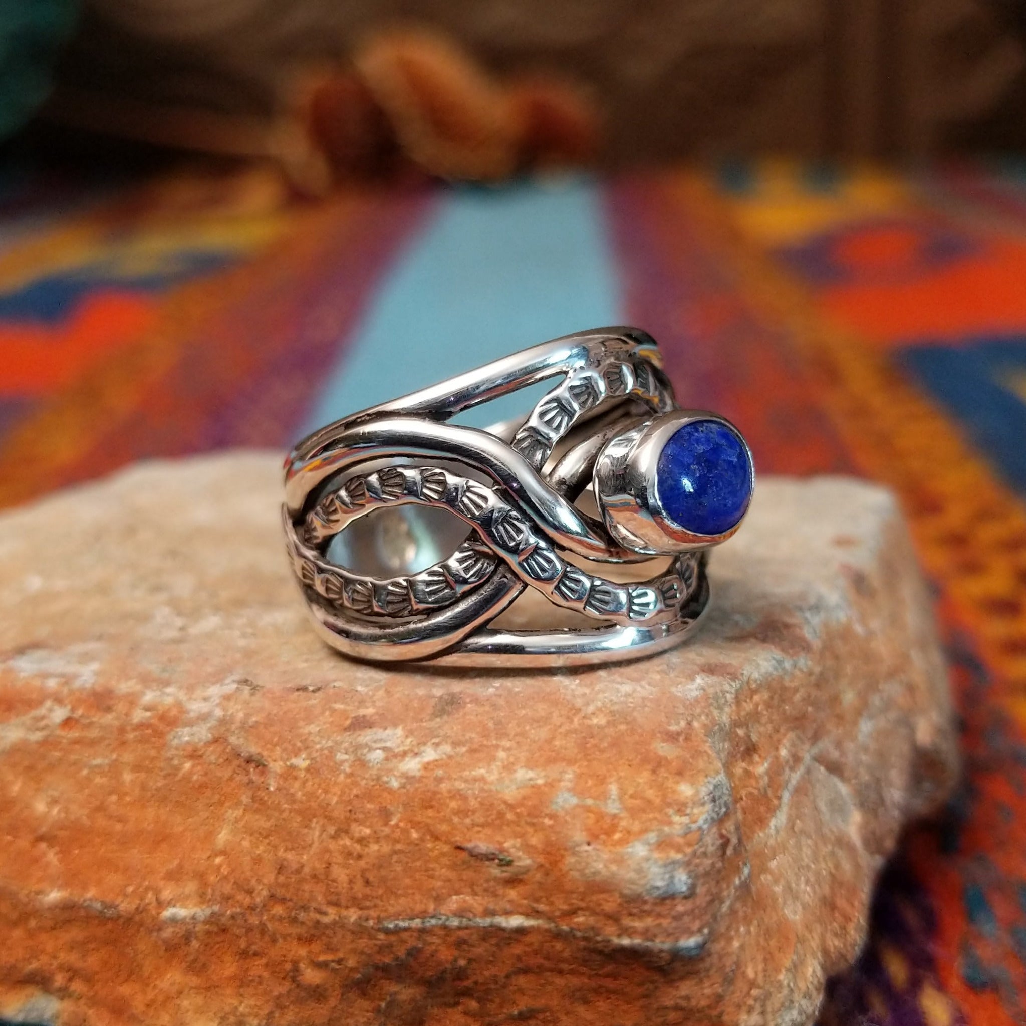 Meandering Lapis Ring by Raymond Coriz featuring an oval blue lapis stone set in Sterling Silver with flowing bands and detailed stamped silver accents; side view.
