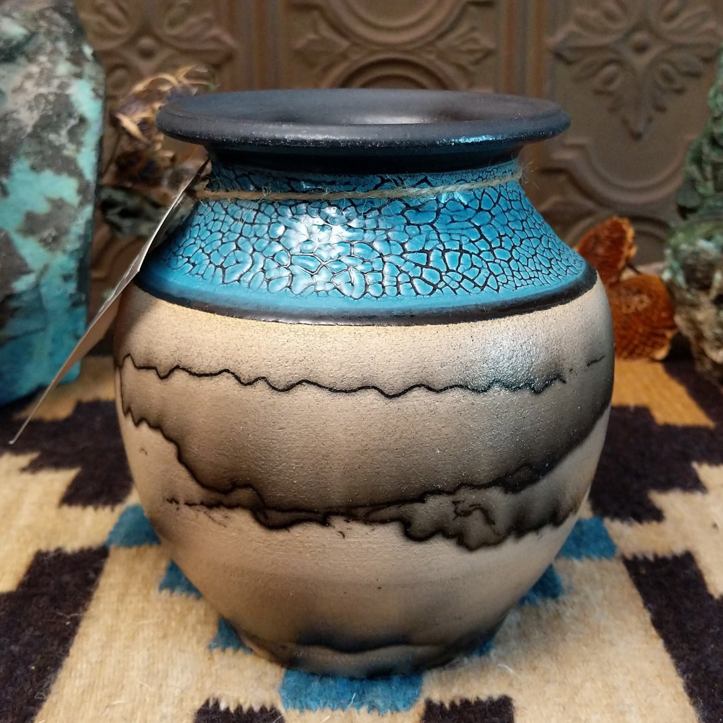 Ceramic pottery piece with horsehair fired onto the face and crackled, blue glazed top-half.