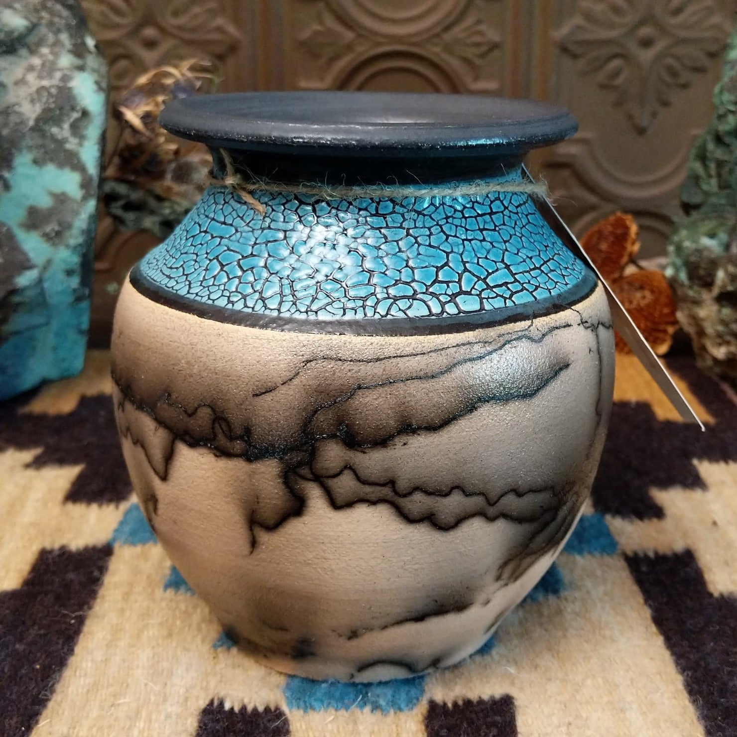 Ceramic pottery piece with horsehair fired onto the face and crackled, blue glazed top-half.
