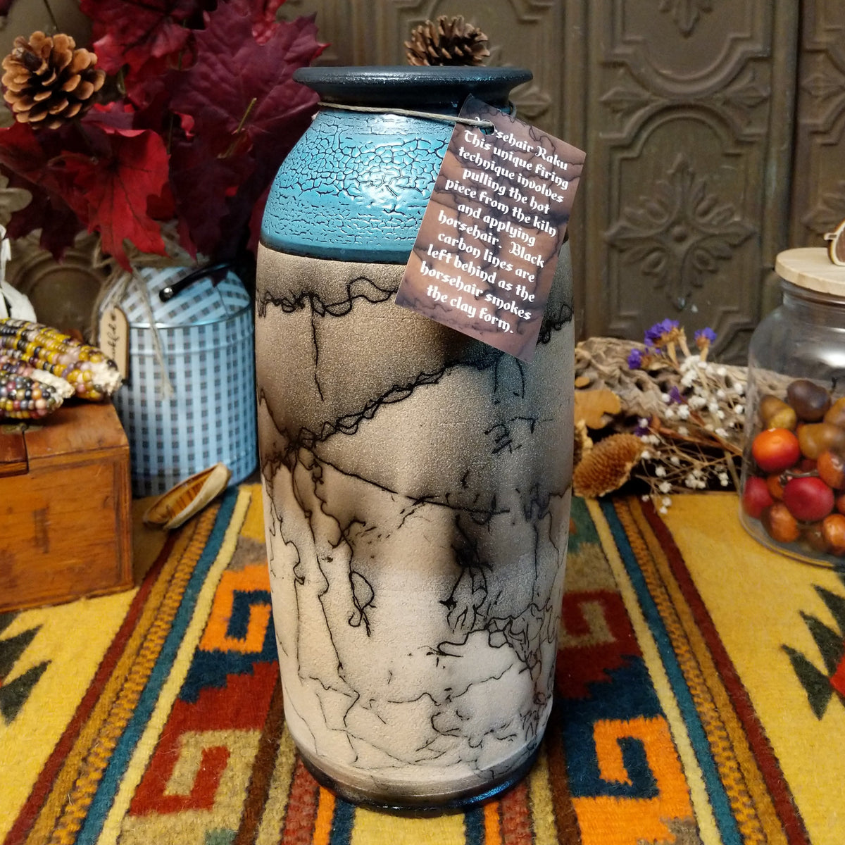 Tall cylindrical horsehair pottery vase by Roger Calhoun with a black rim, crackled turquoise-blue upper section, and branching black horsehair markings on a cream-colored body.