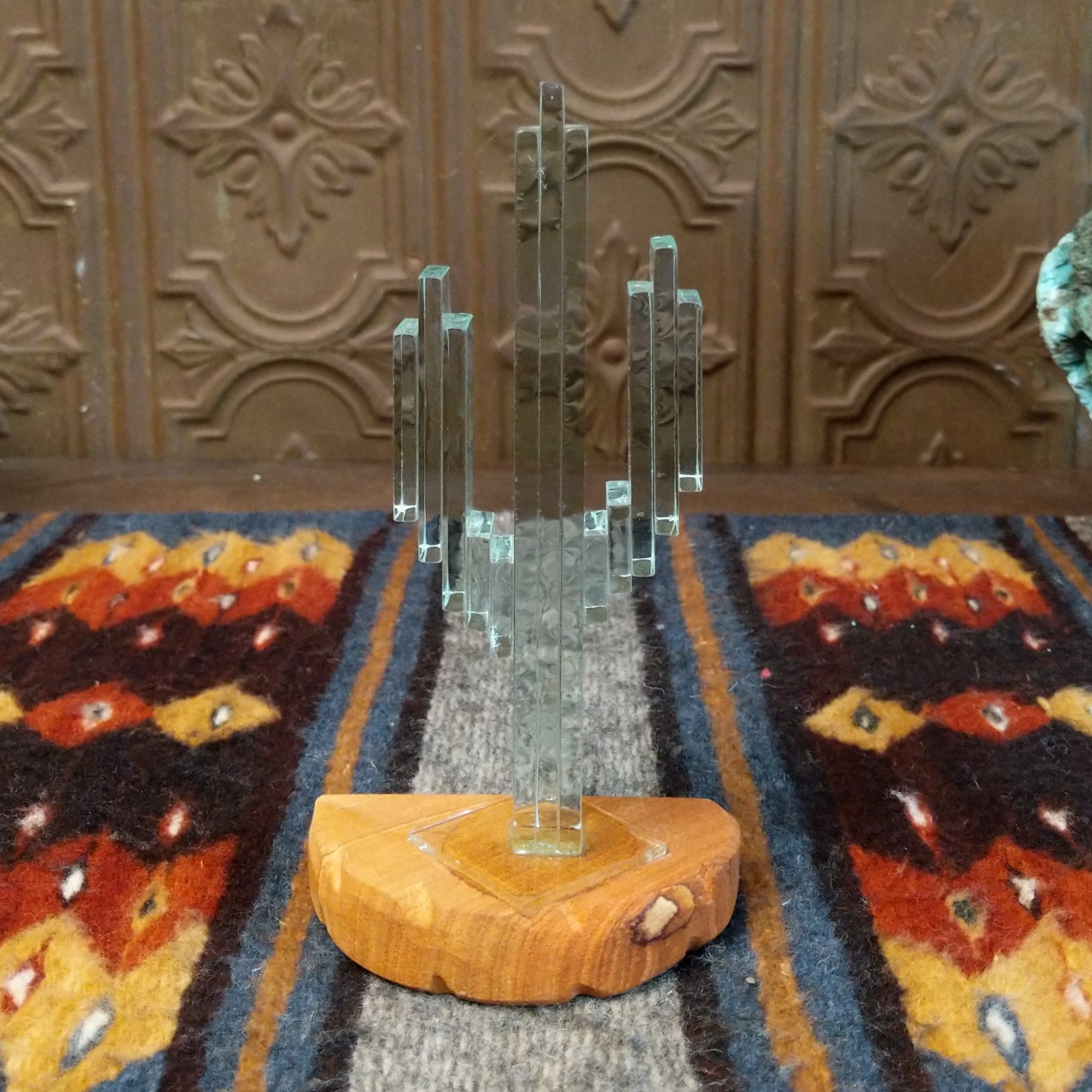 A glass cactus sculpture with translucent aqua glass mounted on a smooth sandstone base.