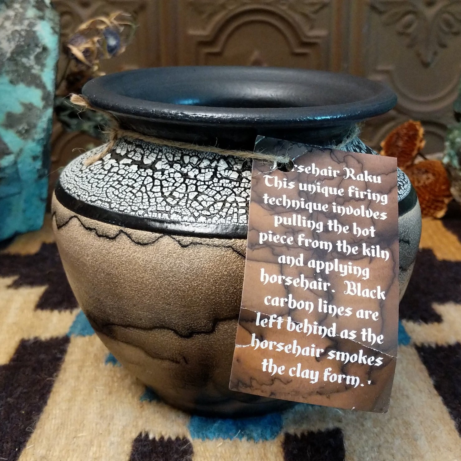 Ceramic pottery piece with horsehair fired onto the surface and white crackled glaze on the top-half.