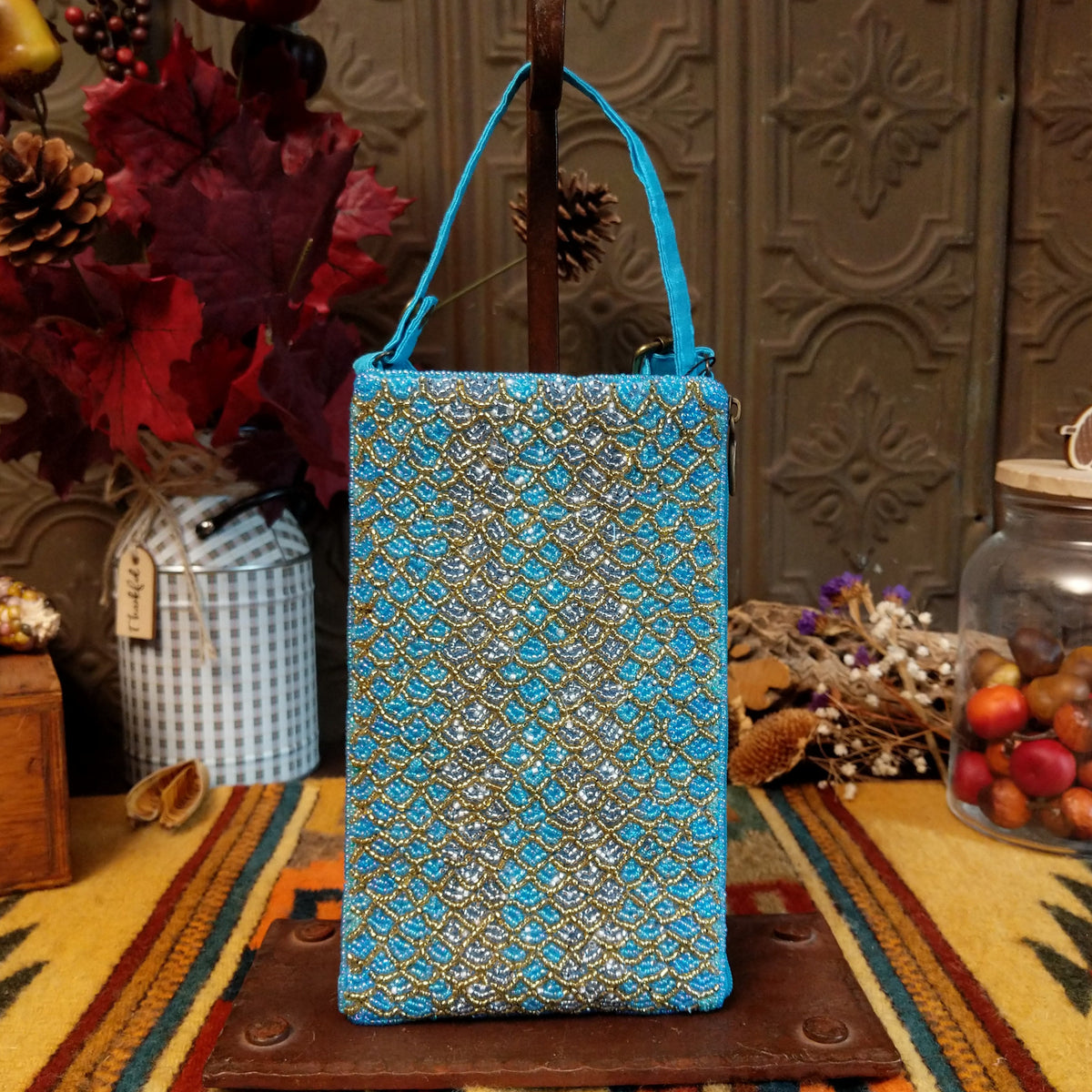 Mermaid Shimmer Club Bag by Bamboo Trading featuring an allover turquoise blue, silver, and gold beaded mermaid-scale pattern with shimmering metallic accents, a compact rectangular silhouette, and a coordinating turquoise blue shoulder strap.