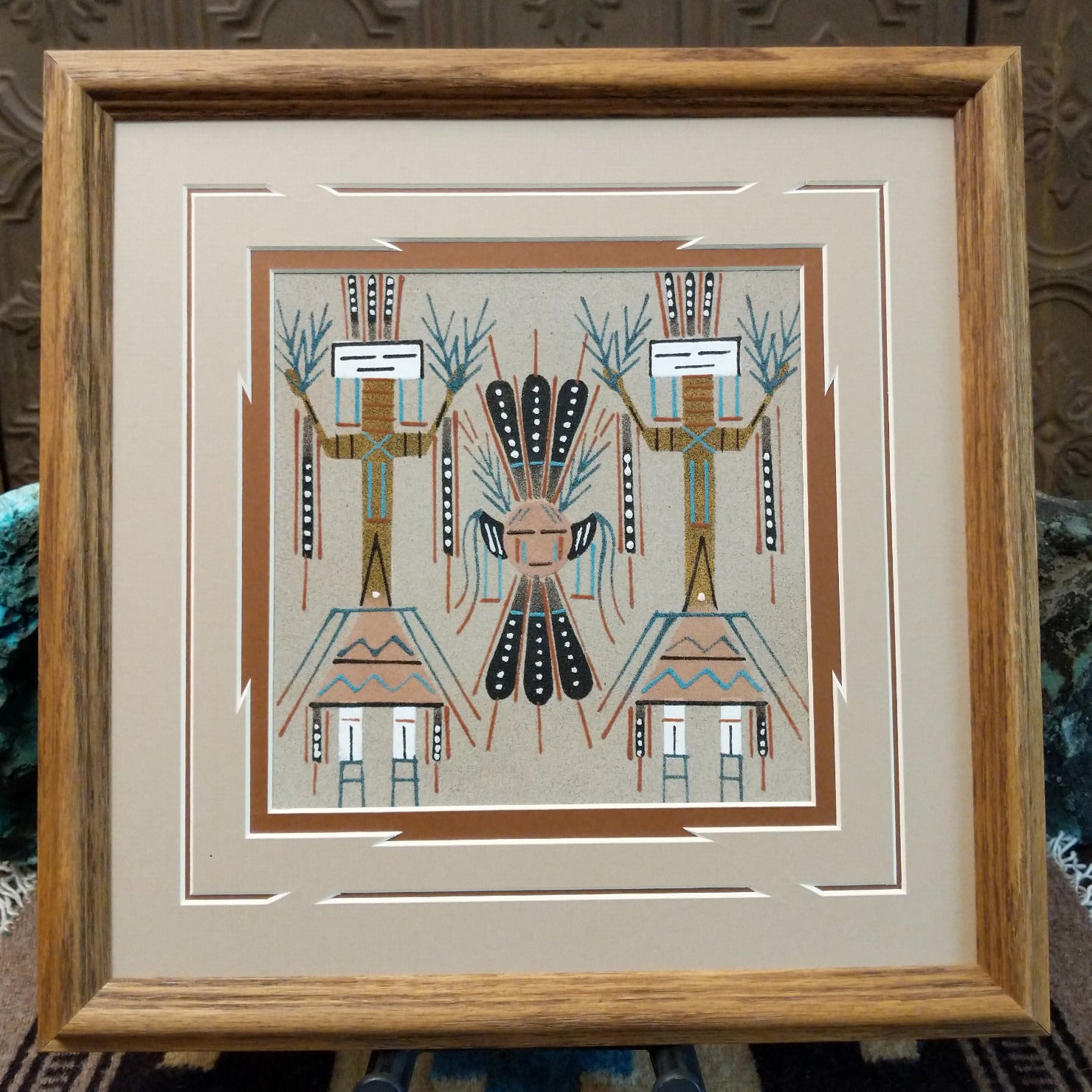 Framed Navajo sand painting of a Moon Yei with mirrored Yei figures and feather details.