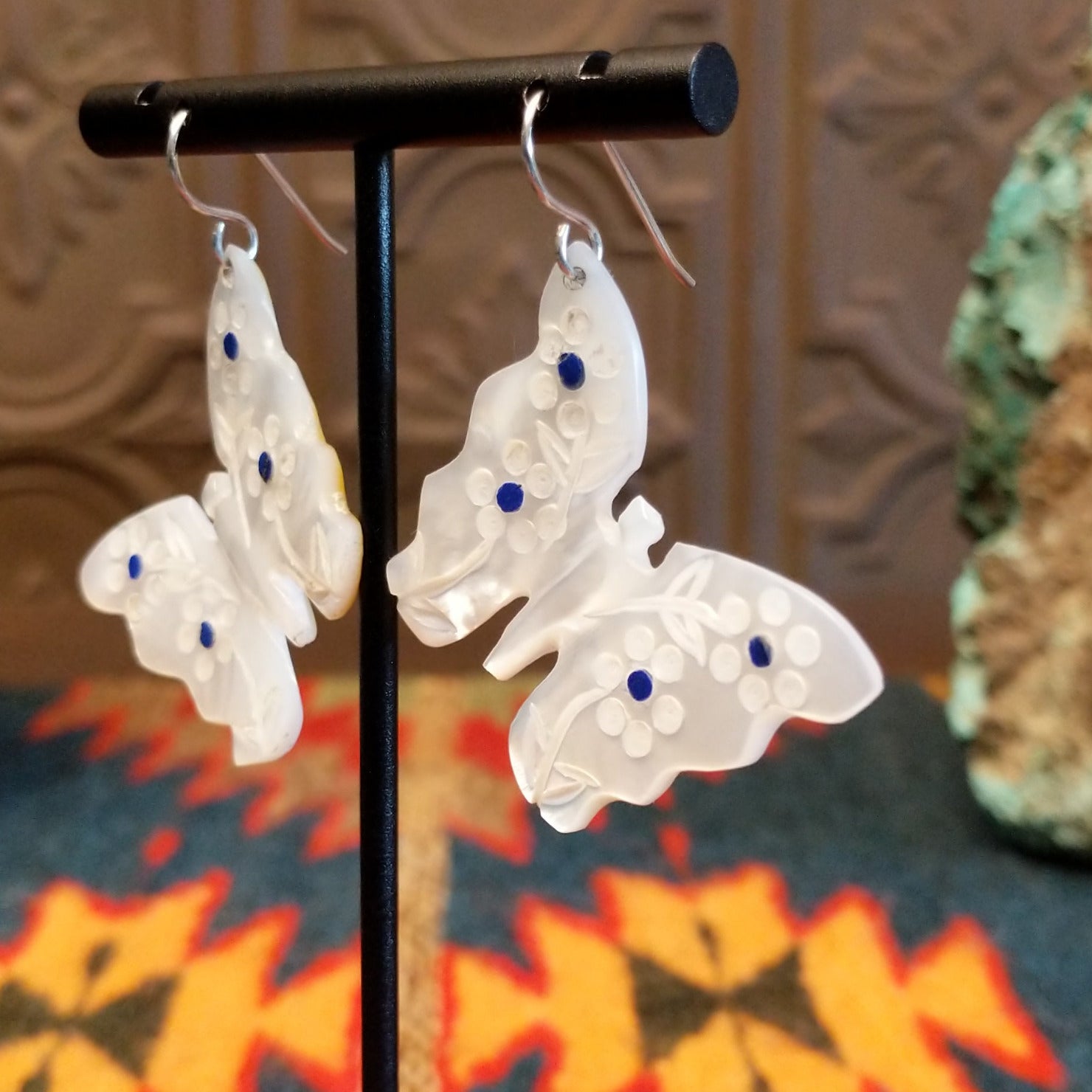 Mother of pearl butterfly earrings with lapis inlaid on the wings, suspended by sterling silver hooks.