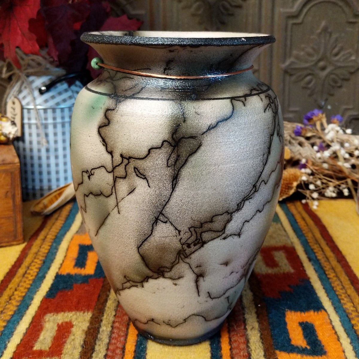 This distinctive Mottled Horsehair Pottery by Roger Calhoun features a tapered ceramic vase with a flared black rim, earthy tones, subtle green accents, flowing black horsehair patterns, and a decorative copper wire with a green bead.