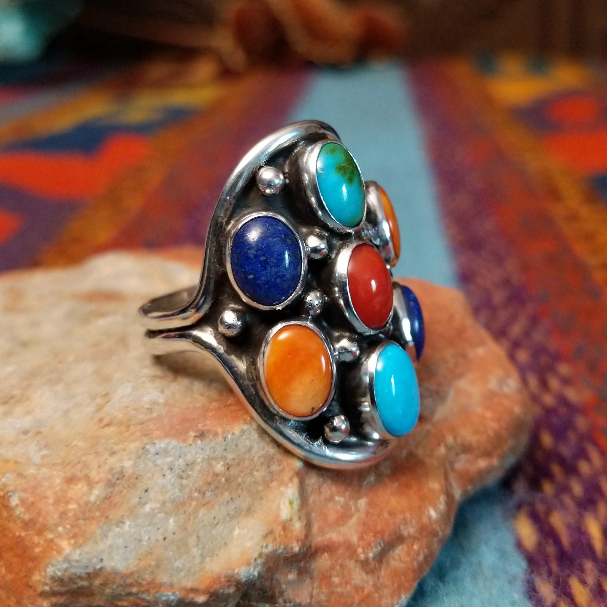 Multistone Cluster Ring by Raymond Coriz featuring turquoise, coral, lapis, and orange-toned stones set in Sterling Silver with polished silver bead accents; side view.