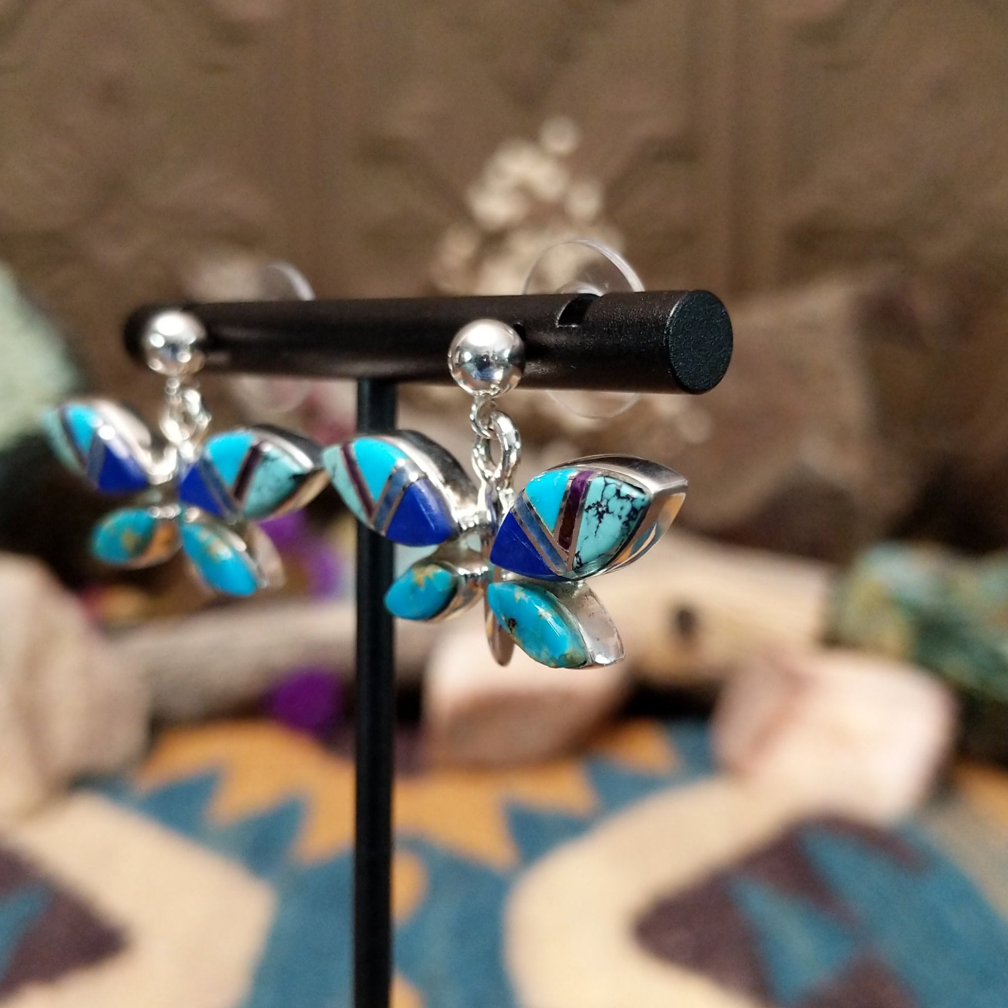 Handcrafted Navajo sterling silver dragonfly earrings by O. James featuring colorful multistone inlay wings in a polished silver dangle design; side view.