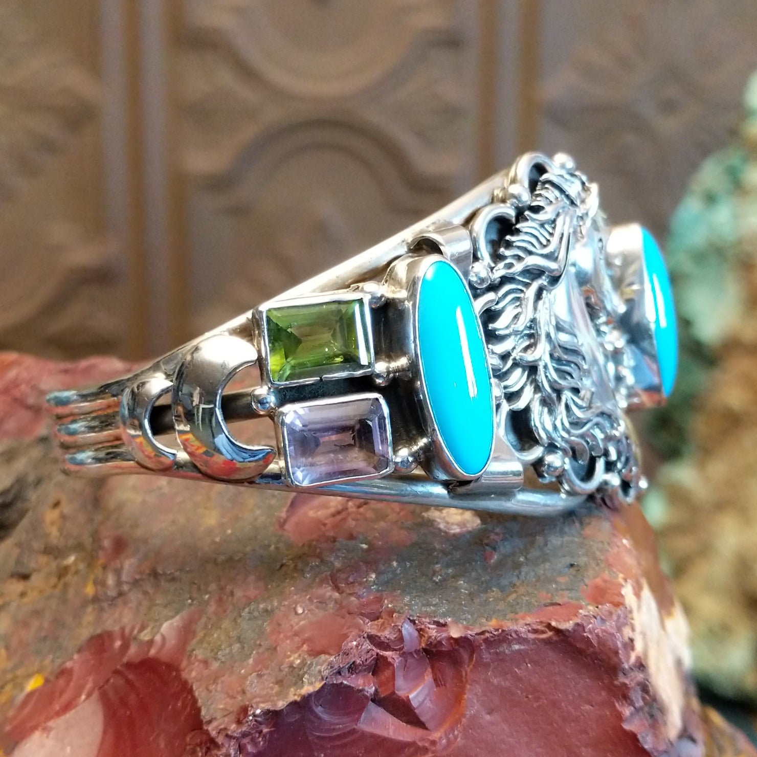 Sterling silver cuff bracelet with horse motif and turquoise, peridot, and amethyst set in bezels.