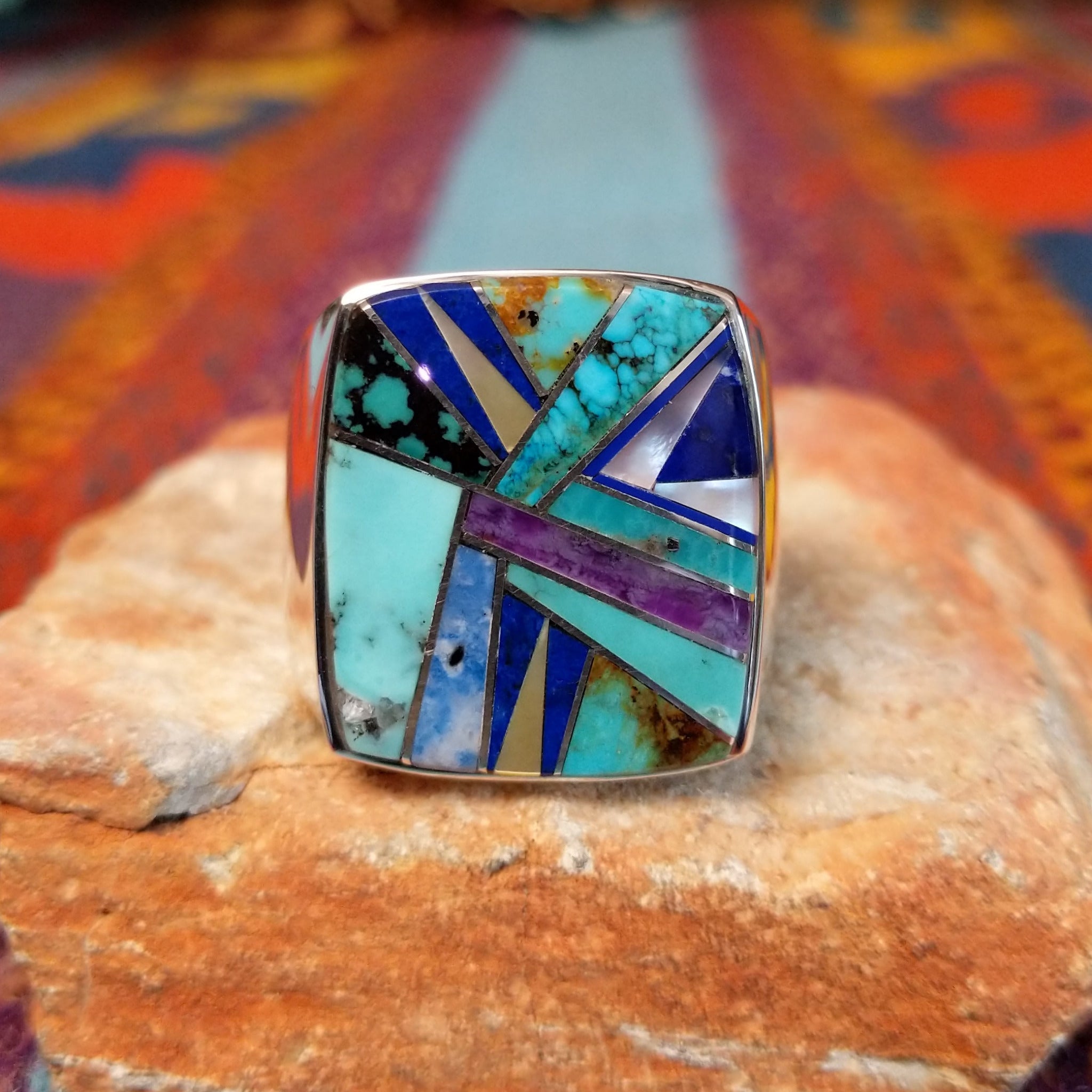 Multistone Inlay Ring by E.D. featuring a large rectangular face with geometric turquoise, blue, purple, cream, and multicolored stone inlay separated by fine silver channels.
