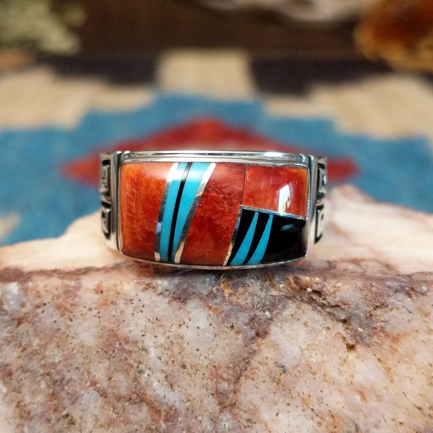 Sterling silver ring with multistone inlay and geometric stamping on the band.