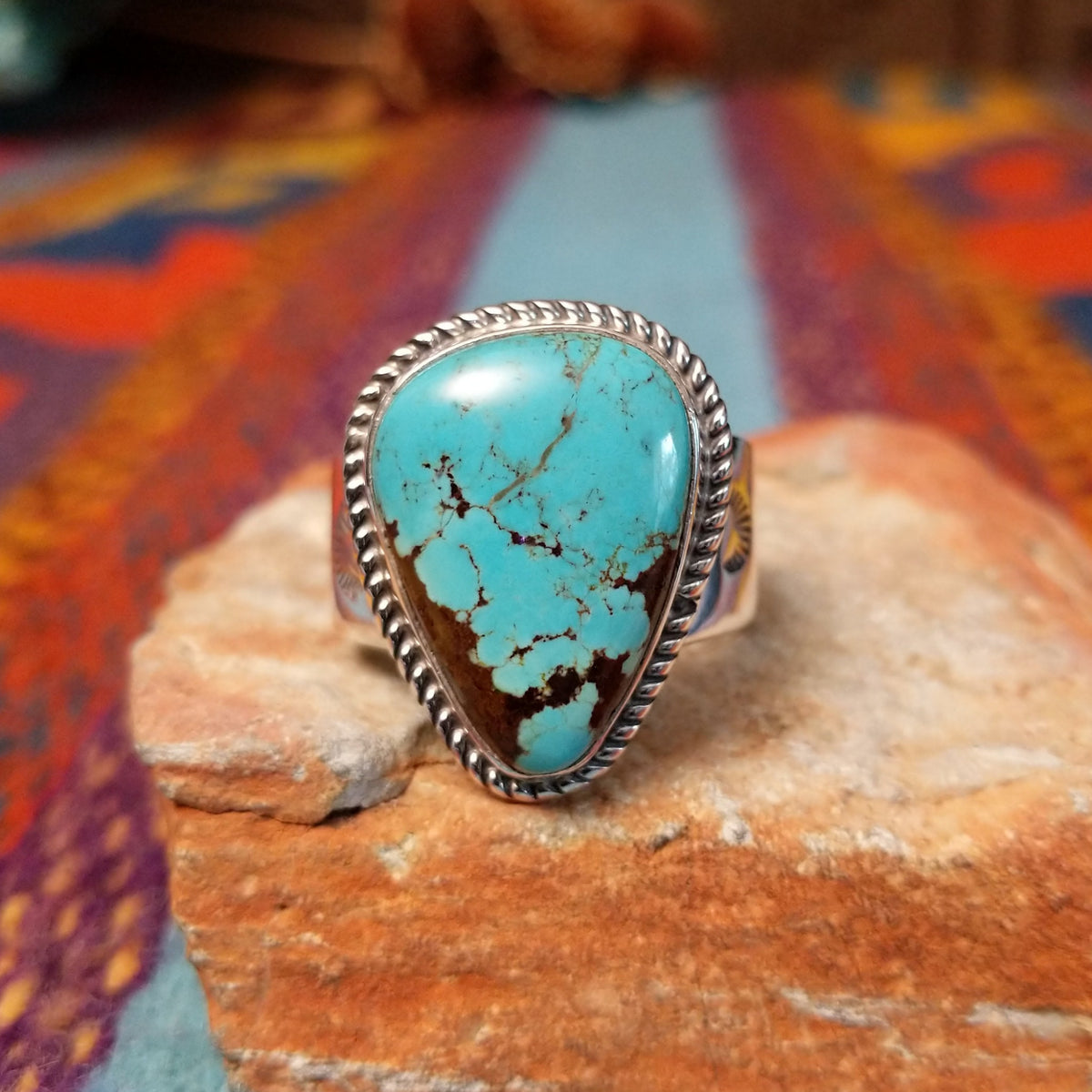 Navajo #8 Turquoise Ring featuring a large freeform blue turquoise cabochon with prominent brown matrix, framed by twisted silver rope detailing in a polished silver setting.