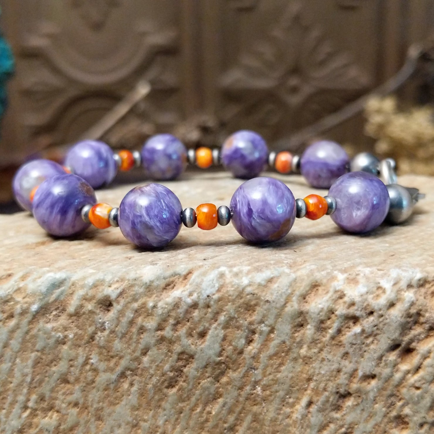 Beaded charoite bracelet with accents of sterling silver and orange spiny oyster shell.