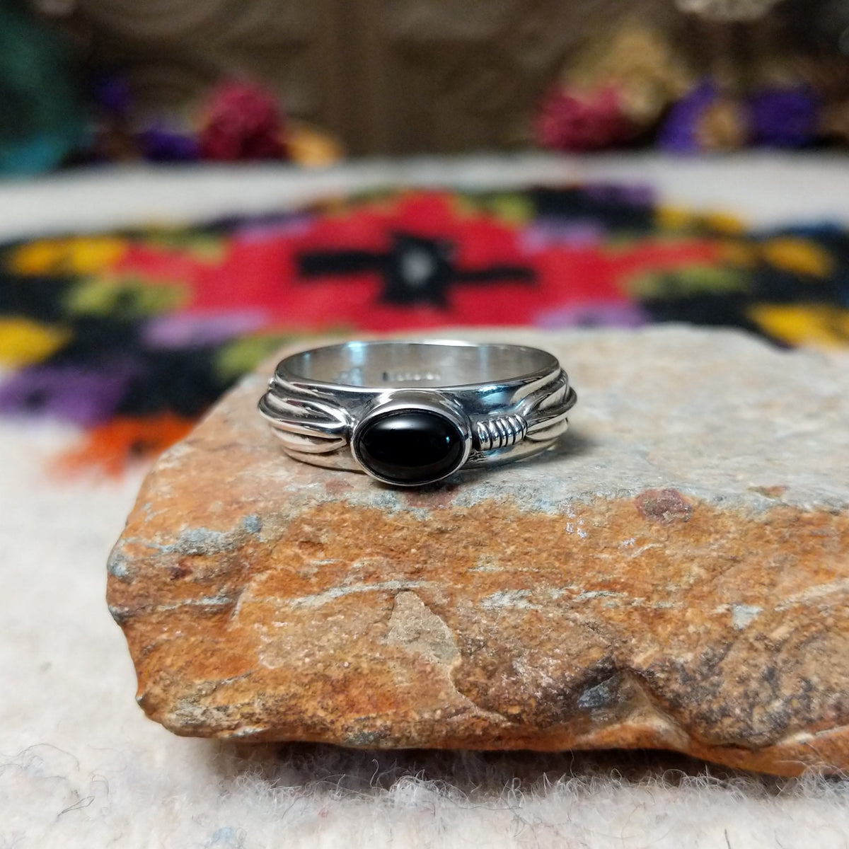 Refined Navajo Black Onyx Feather Ring featuring a polished oval black onyx stone set in sterling silver with detailed feather-inspired silverwork along the band.