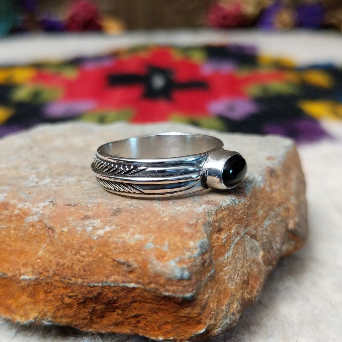 Refined Navajo Black Onyx Feather Ring featuring a polished oval black onyx stone set in sterling silver with detailed feather-inspired silverwork along the band; side view.