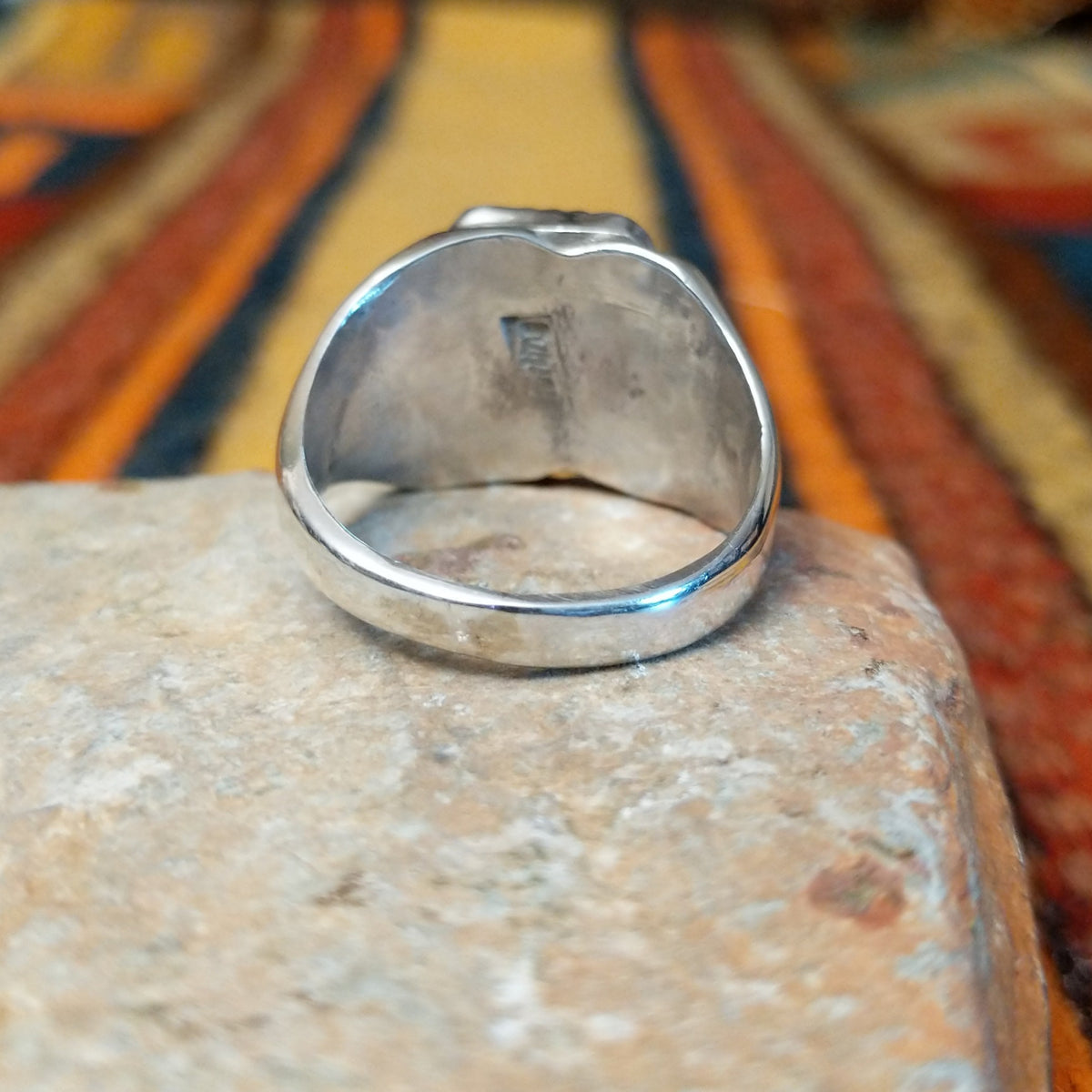 Navajo Black Onyx Ring featuring a polished rectangular black onyx gemstone in a sawtooth silver bezel, with a wide silver band accented by stamped fan-shaped designs on both sides; underside view.