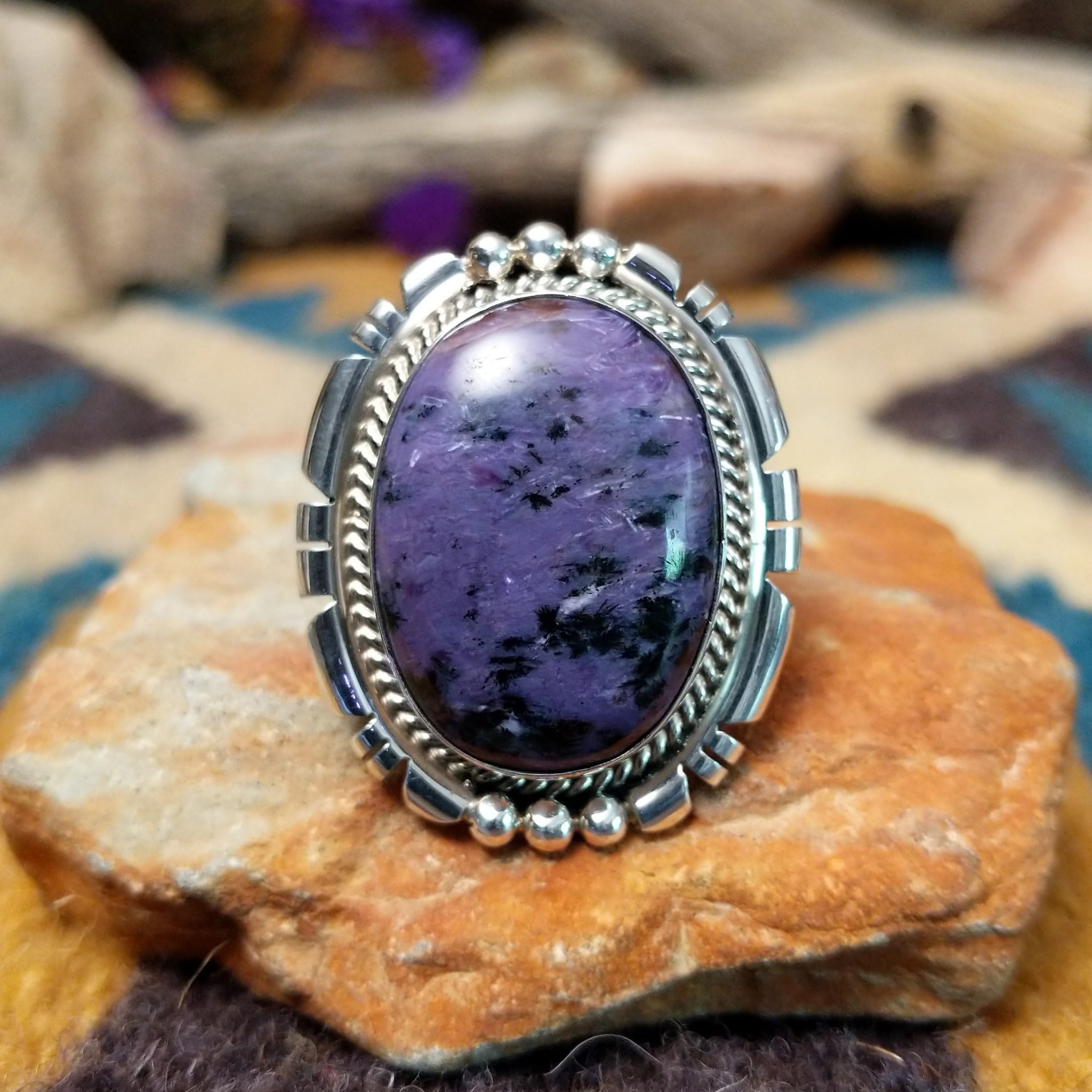 Navajo sterling silver ring with an oval Charoite stone in shades of purple with natural black inclusions.