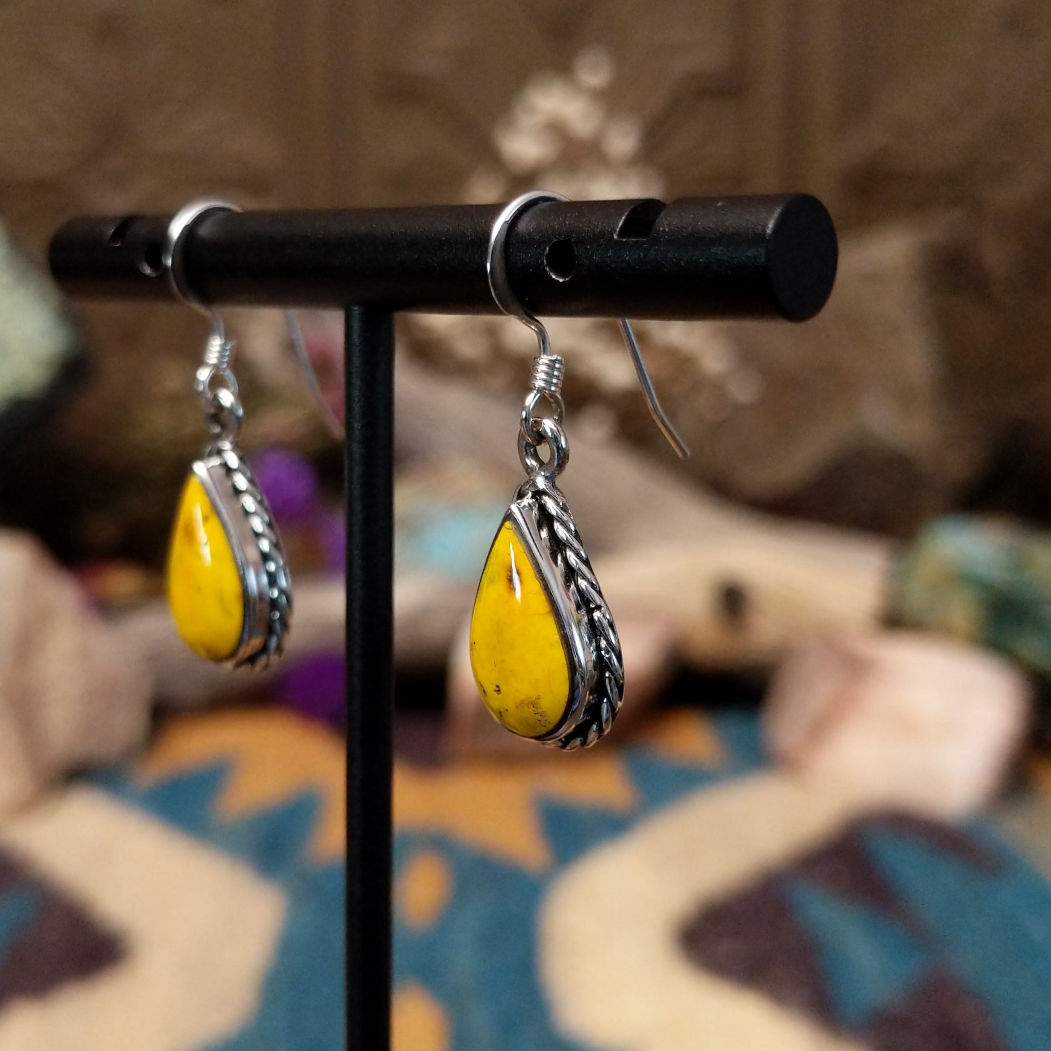 Handcrafted Navajo sterling silver teardrop earrings featuring vibrant Bumblebee Jasper cabochons with golden-yellow tones, natural earthy inclusions, and twisted rope border detailing; side view.