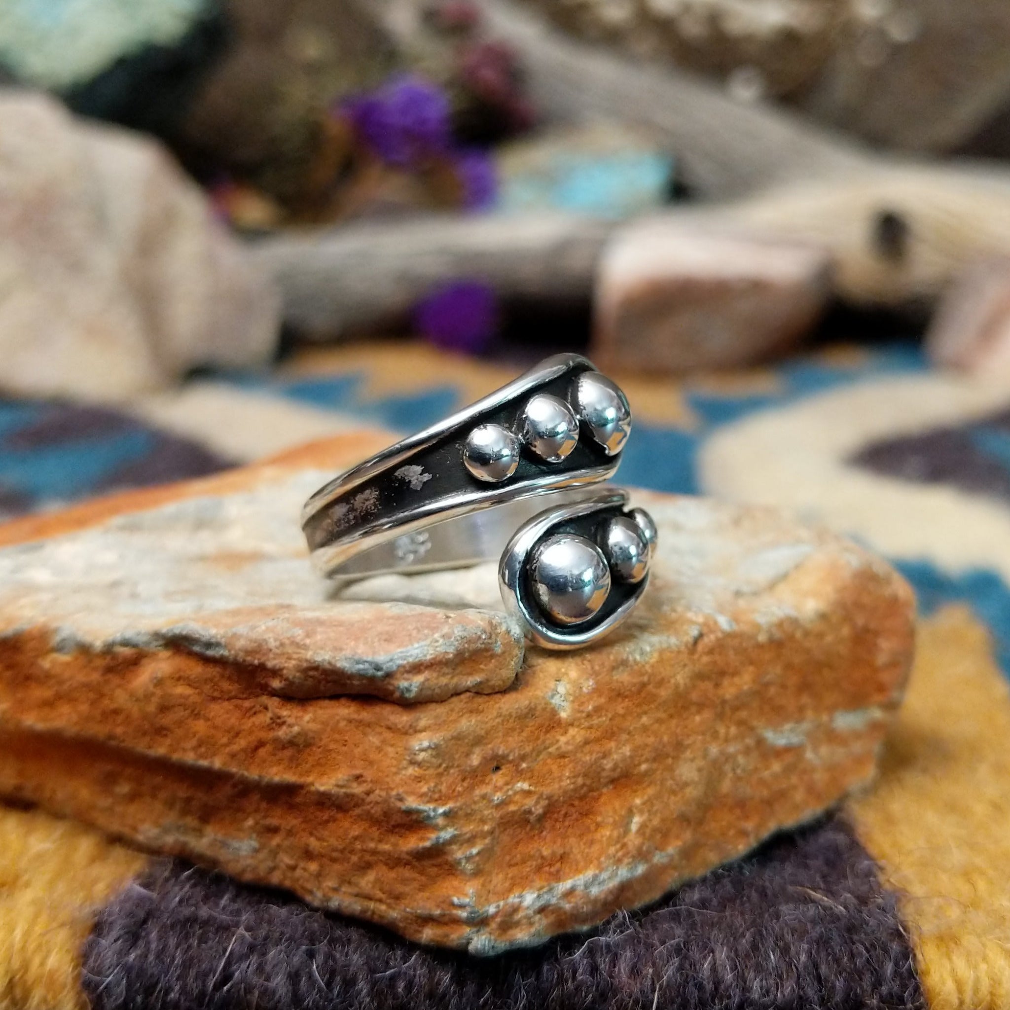 Handcrafted Navajo sterling silver bypass ring featuring graduated polished silver domes set in oxidized open-ended bezels, creating a modern Southwestern statement design; side view.