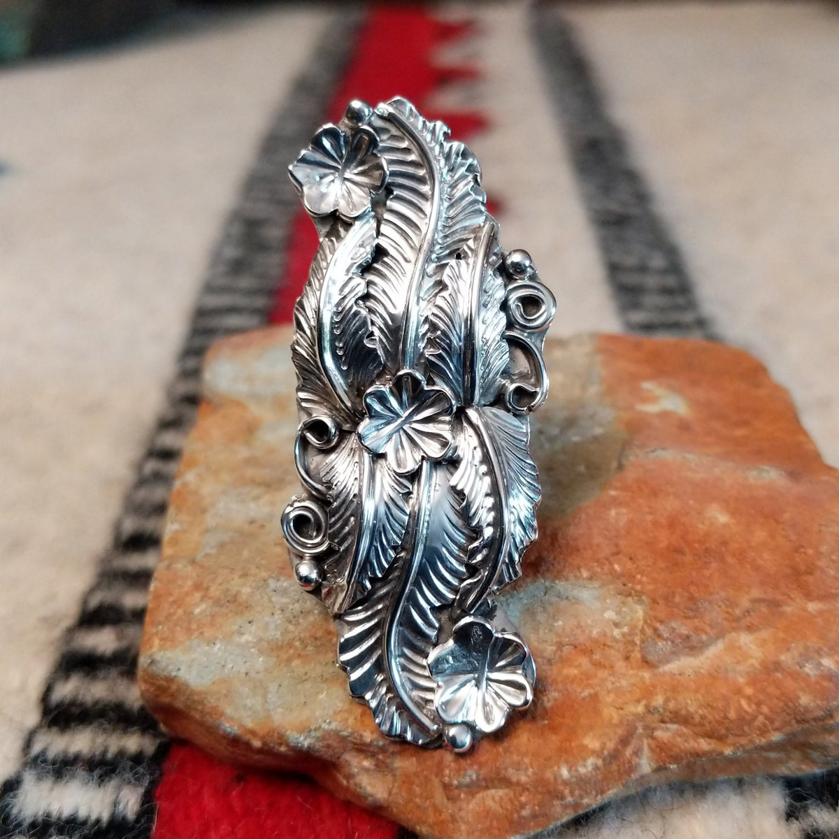 Navajo silver ring with layered feathers, flowers, and curled wire accents.