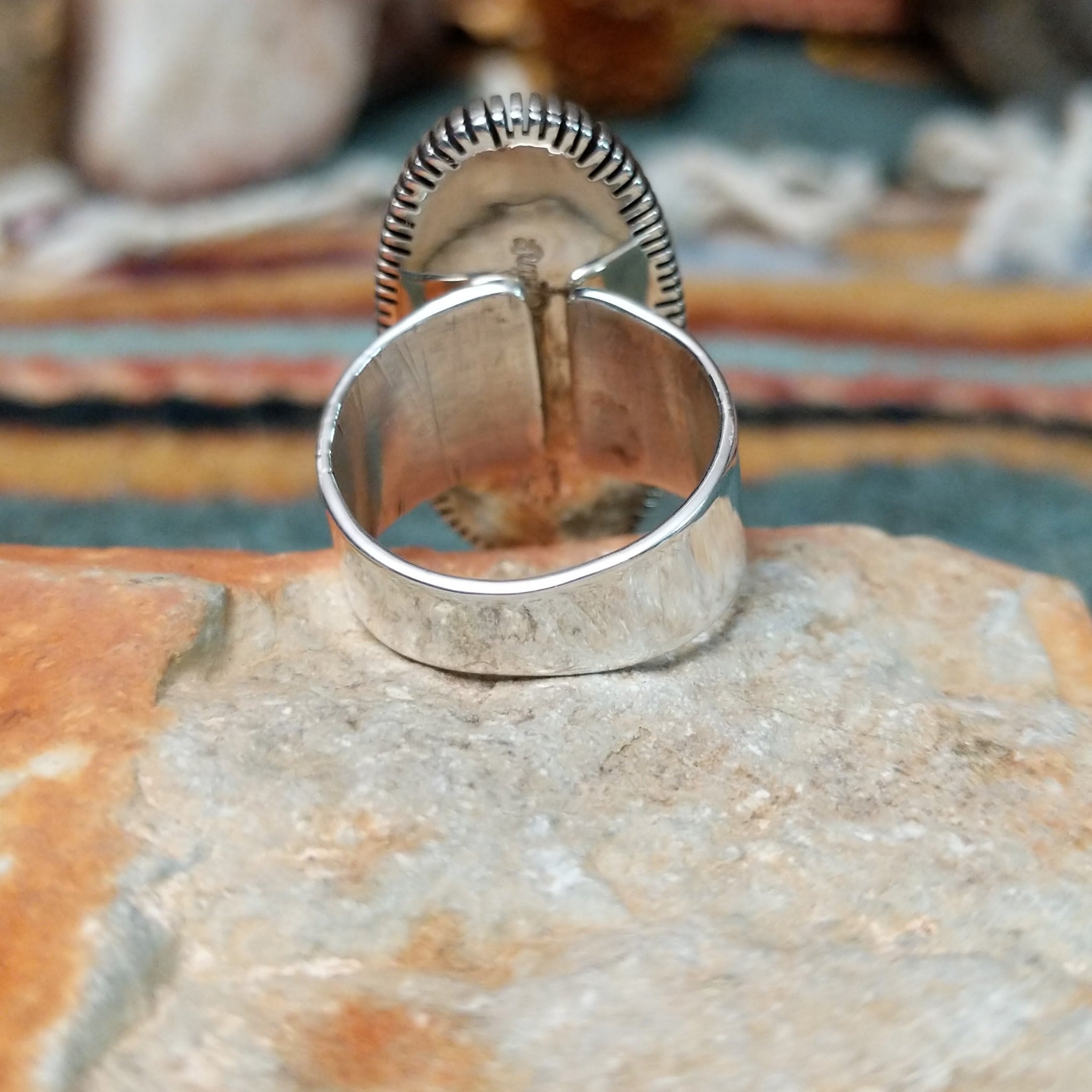 Navajo sterling silver ring featuring an elongated purple charoite stone framed by twisted silver rope and detailed radiating silverwork; underside view.