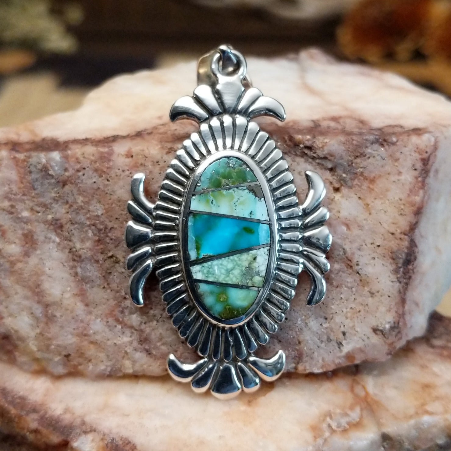 Sterling silver pendant with turquoise inlaid in the oval bezel, framed by fanned silverwork.